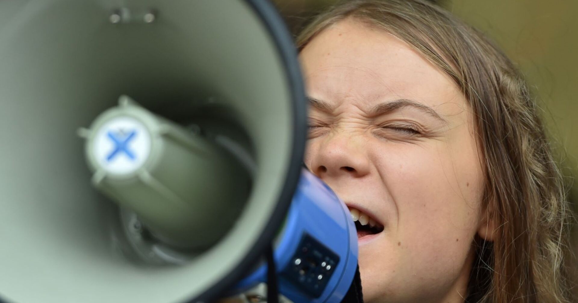 Greta Thunberg schreit mit geschlossenen Augen in ein Megaphon