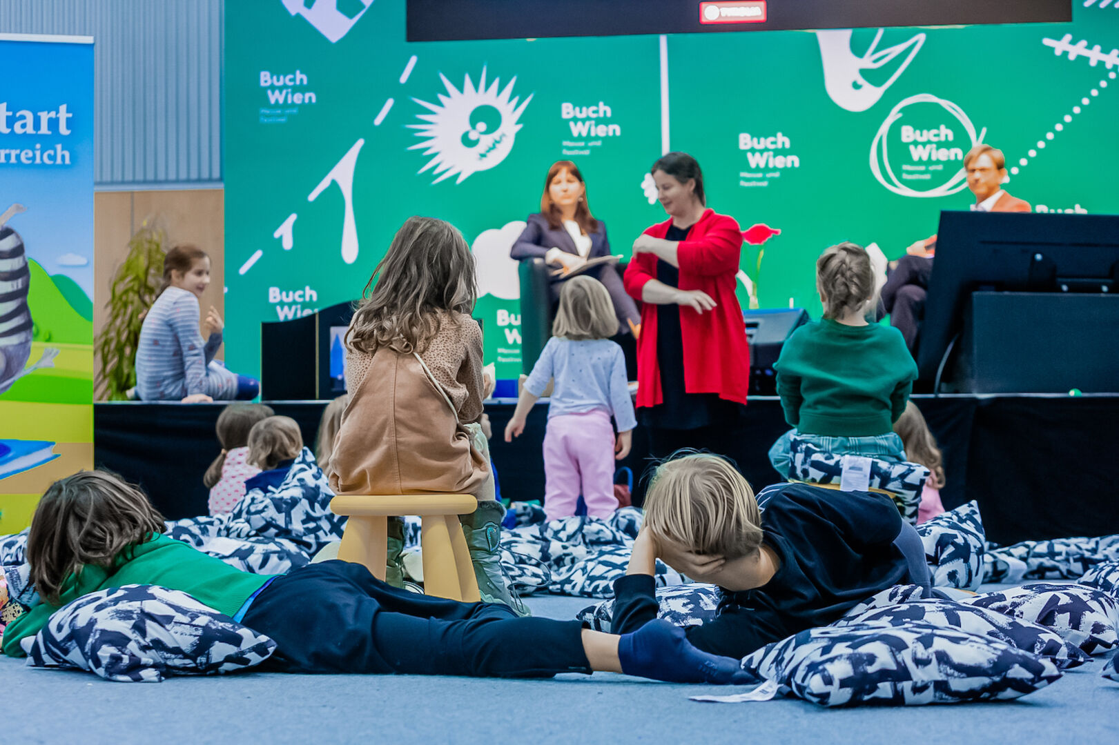 Kinder liegen auf und hüpfen um Kissen herum