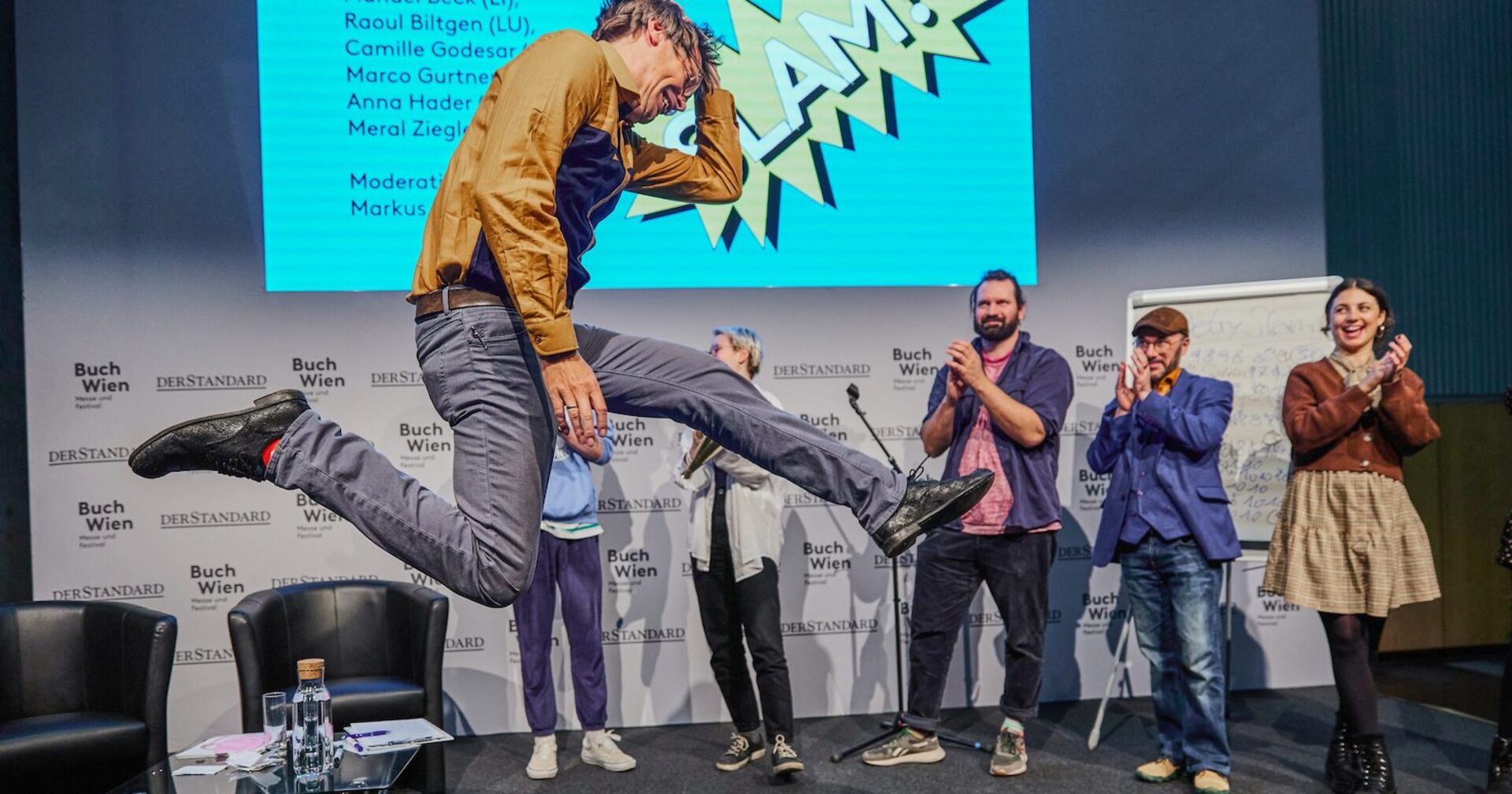 Ein junger Mann springt auf einer Bühne in die Höhe
