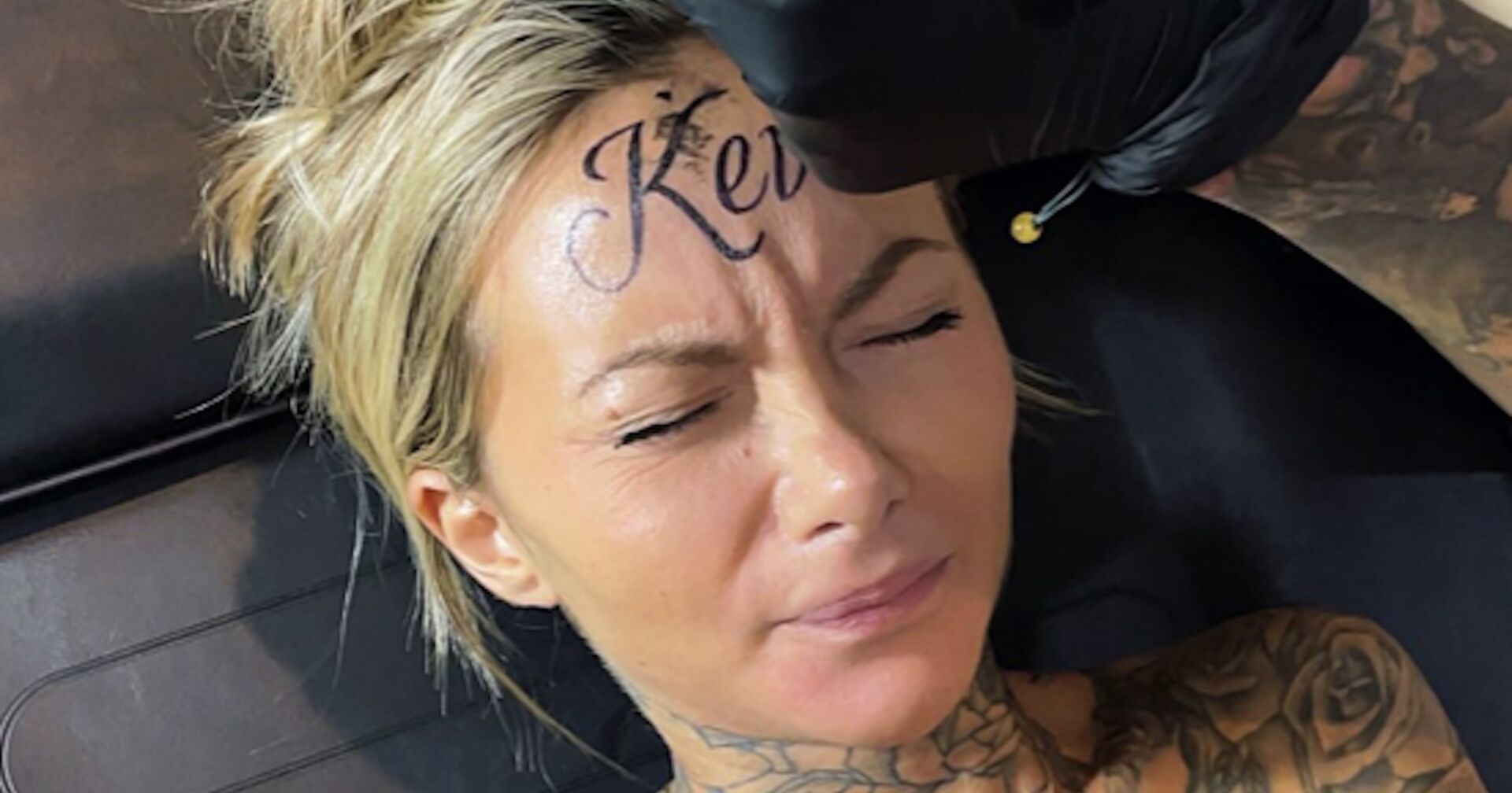 Eine Frau mit blonden Haaren lässt sich "Kevin" auf ihre Stirn tätowieren.