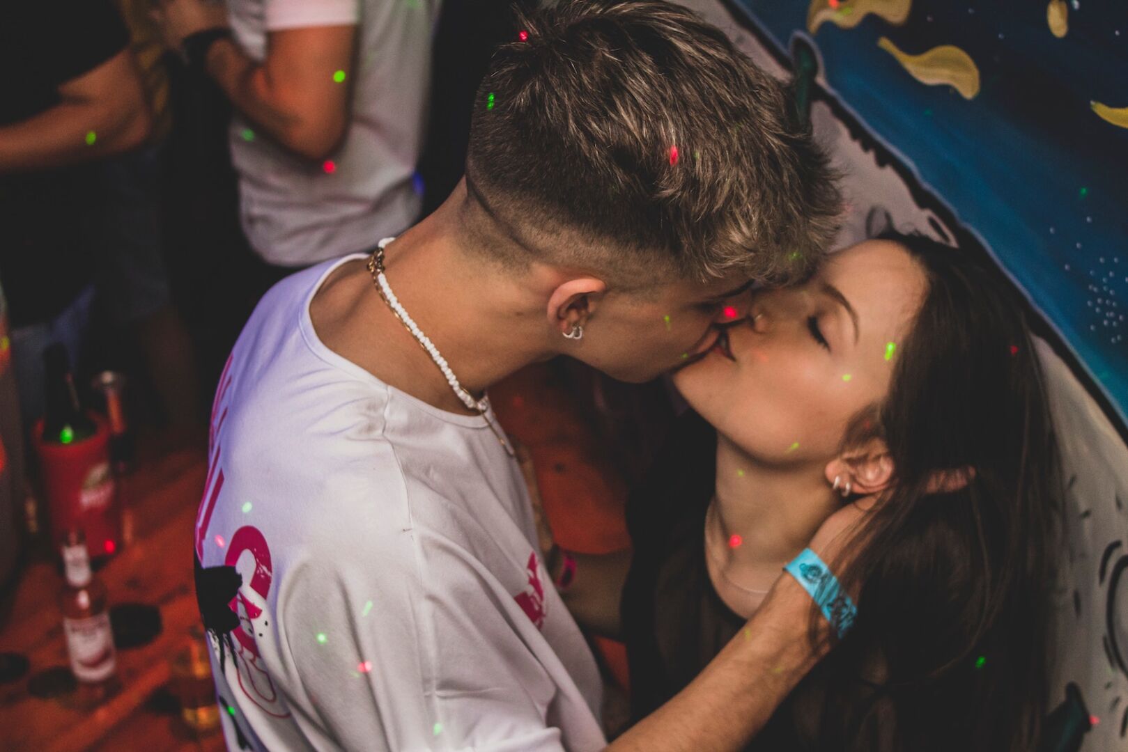Zwei Menschen küssen sich auf einer Party.