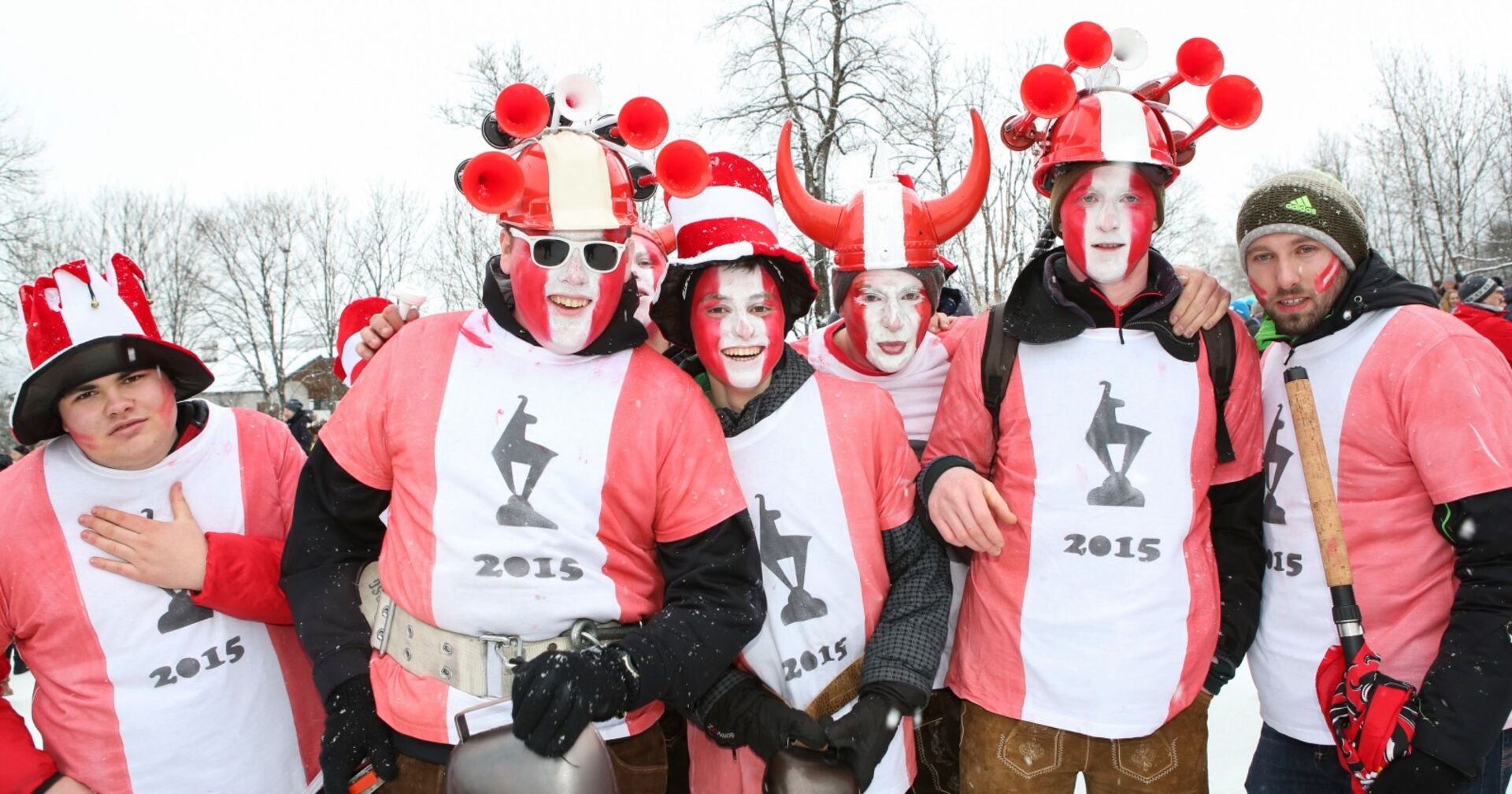 Eine Gruppe österreichischer Ski-Fans mit bemalten Gesichtern, Kuhglocken und Tröten auf der Streif in Kitzbühel
