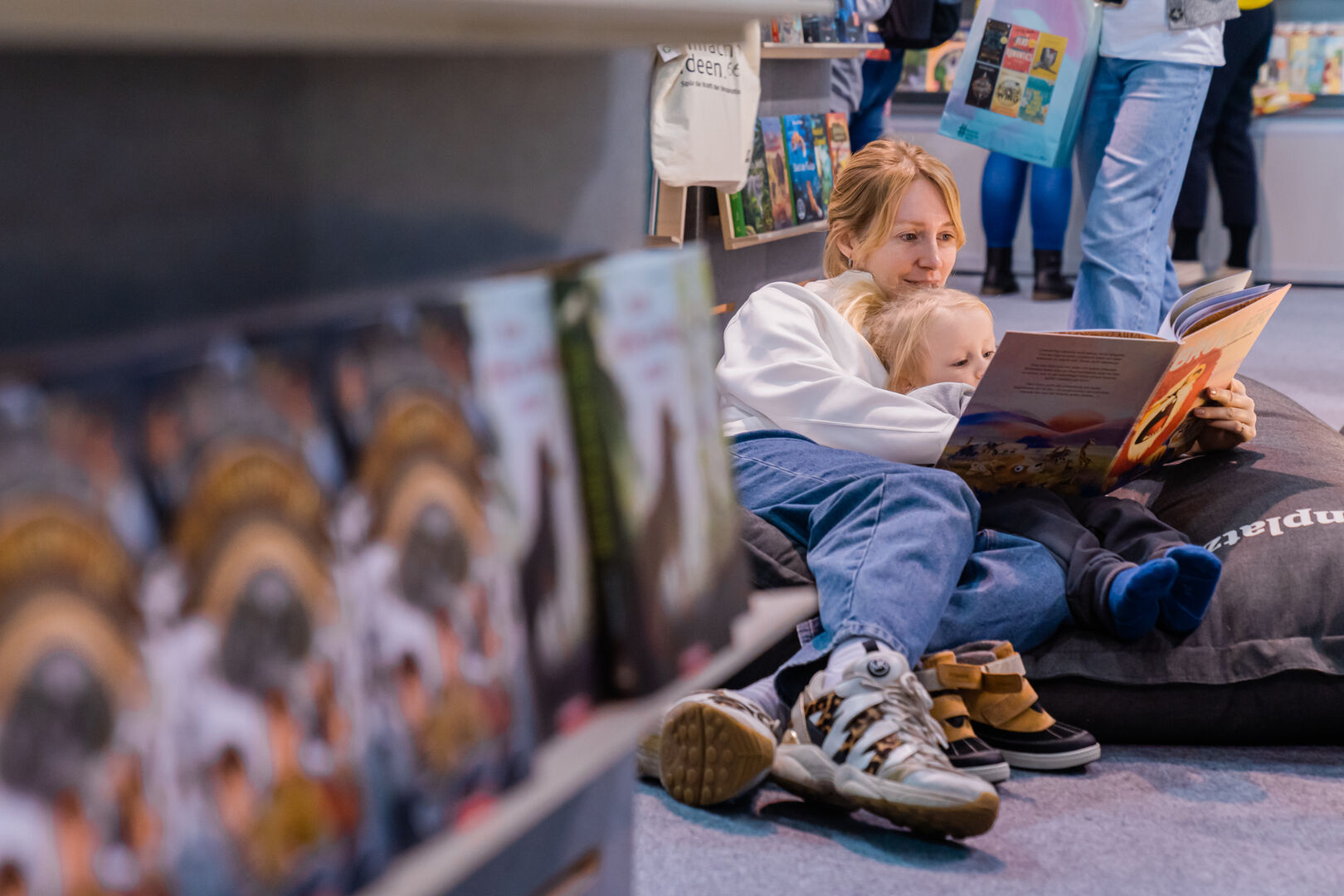 Eine Mutter und ihr kleines Kind haben es sich auf der Buch Wien 23 in einem Sitzsack gemütlich gemacht und schmökern gemeinsam in einem Buch