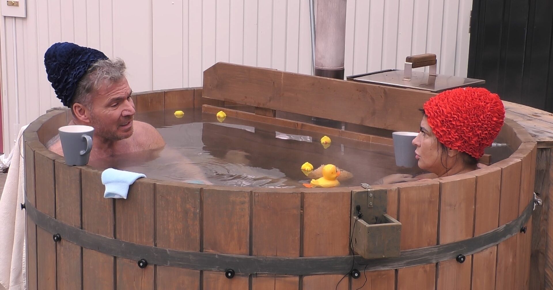Peter Klein trägt eine schwarze Badehaube. Iris Klein eine rote Badehaube. Beide sitzen ins in einem warmen Whirlpool.