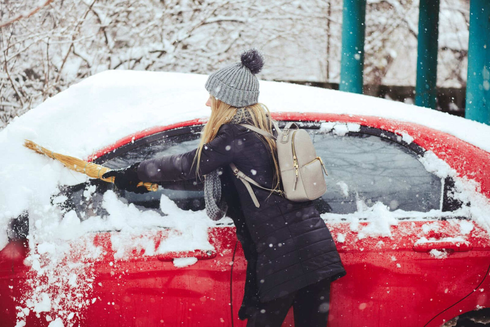 Eine Frau befreit ihr rotes Auto von Schnee.