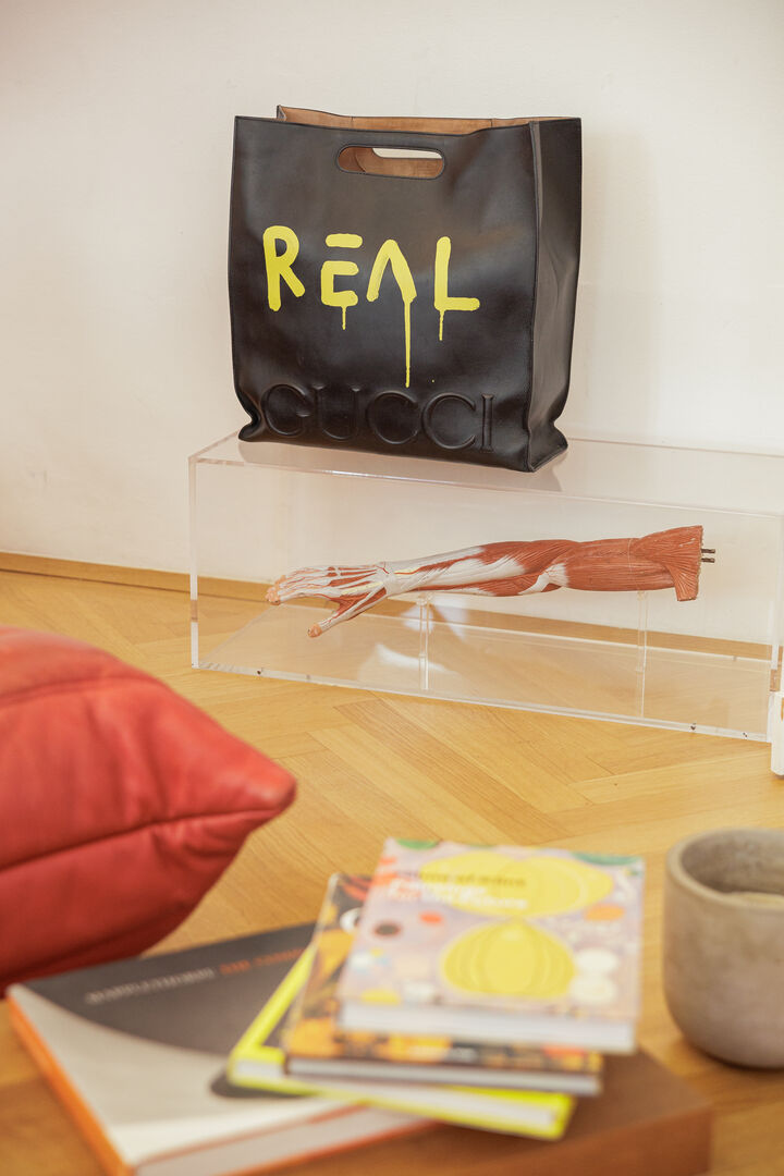 Eine Shopping-Tüte mit Logo und ein Unterarm in einer Glasbox