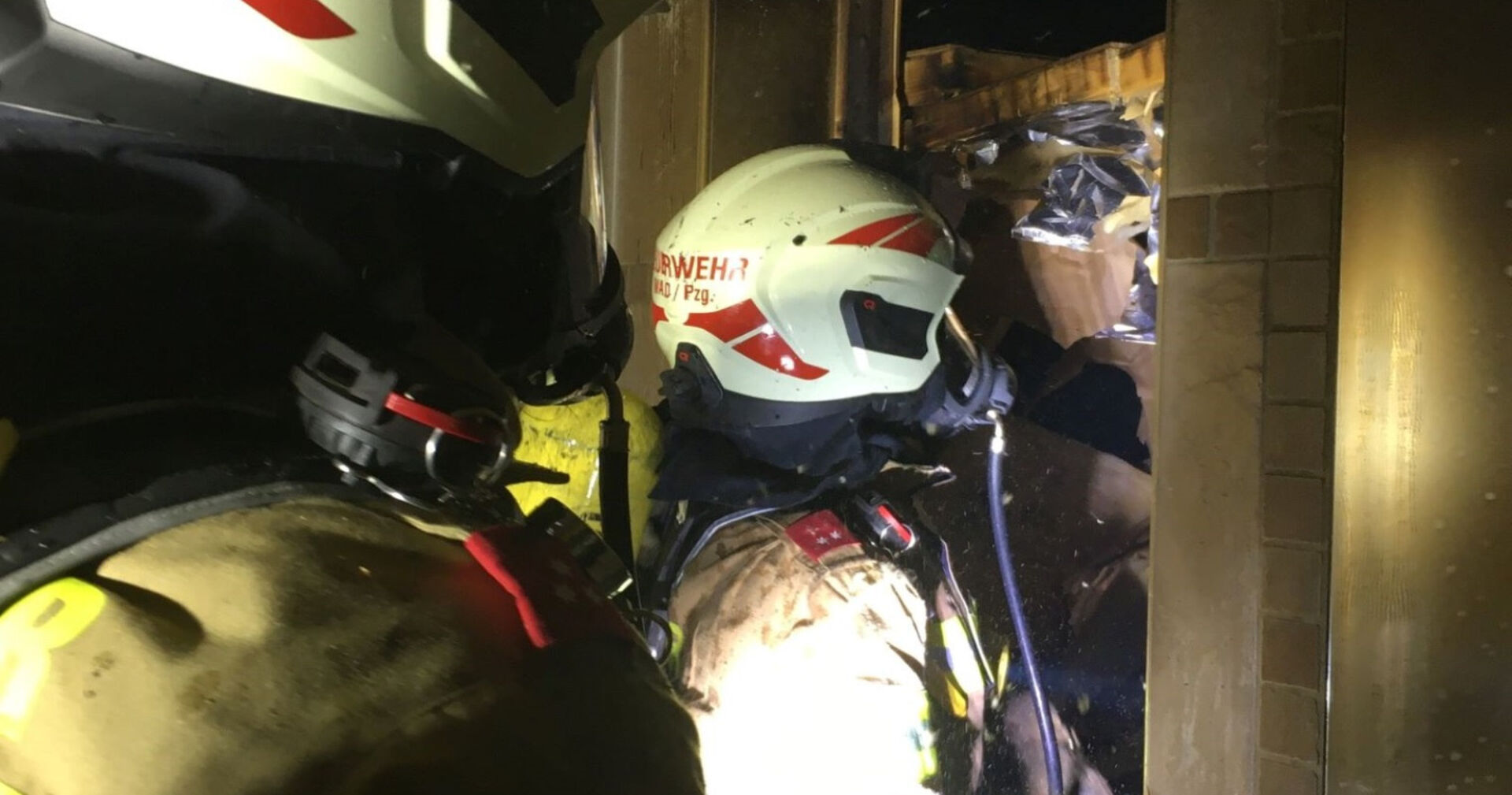 Zwei Feuerwehrmänner dringen zu einem Saunabrand vor.