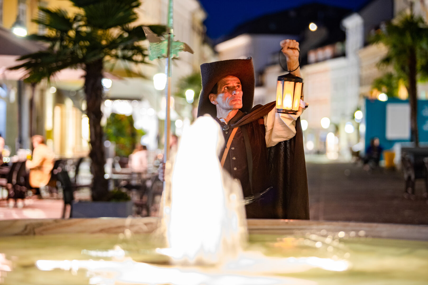 Horst Ragusch mit Laterne in der Hand vor Springbrunnen