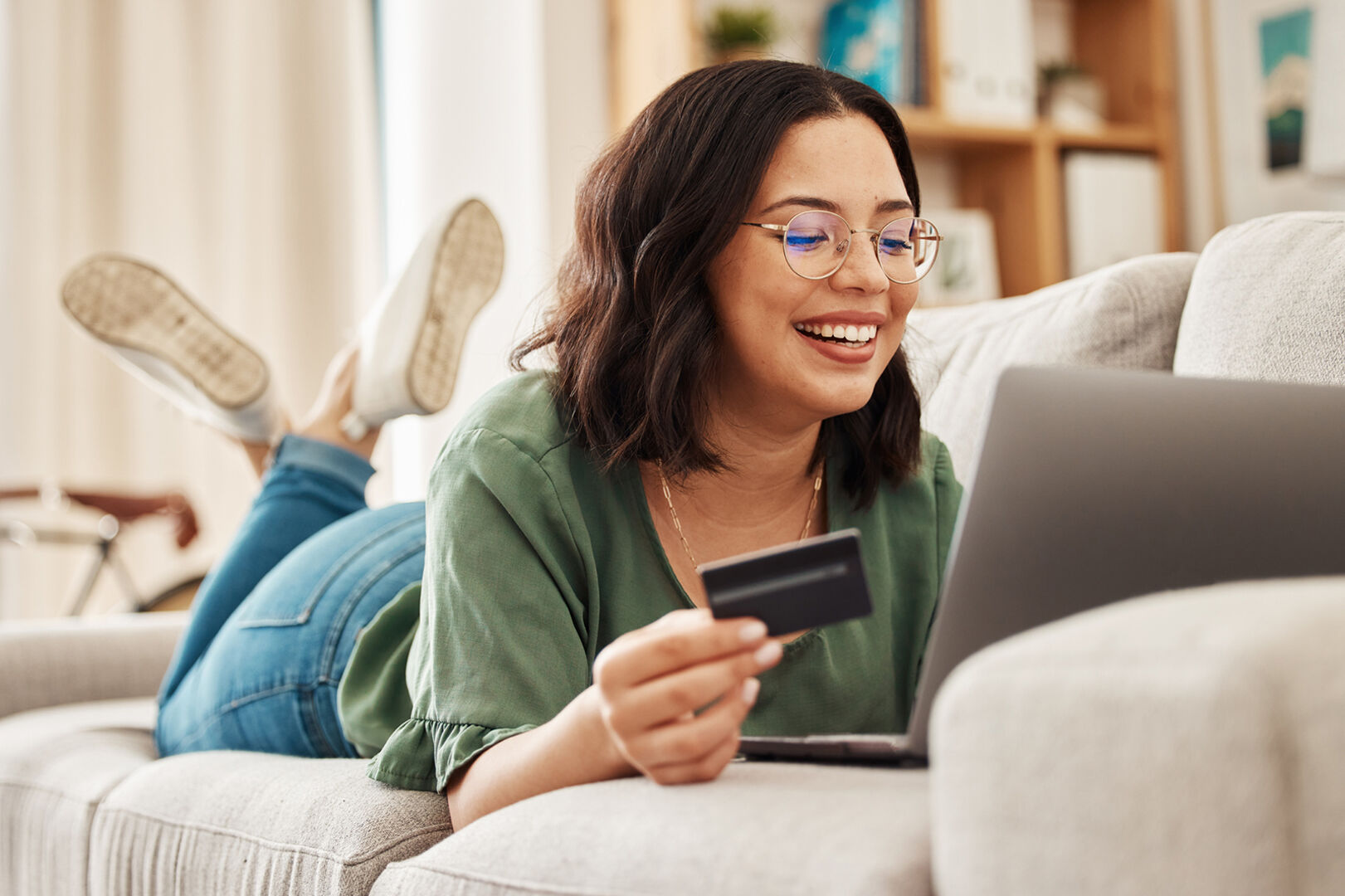 Frau liegt auf der Couch mit Notebook | Credit: iStock.com/Jacob Wackerhausen