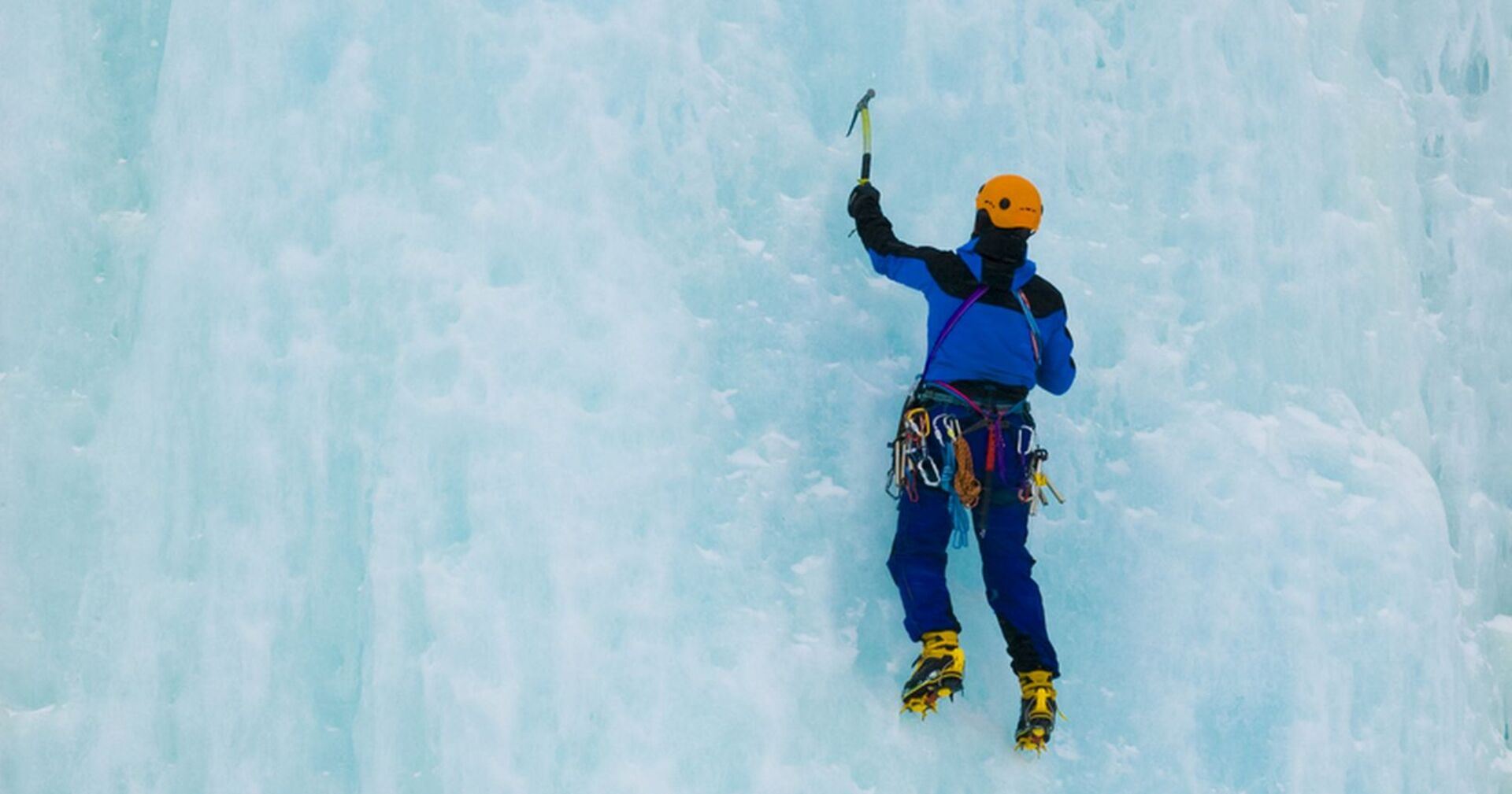 Ein Alpinist klettert einen vereisten Wasserfall hoch.