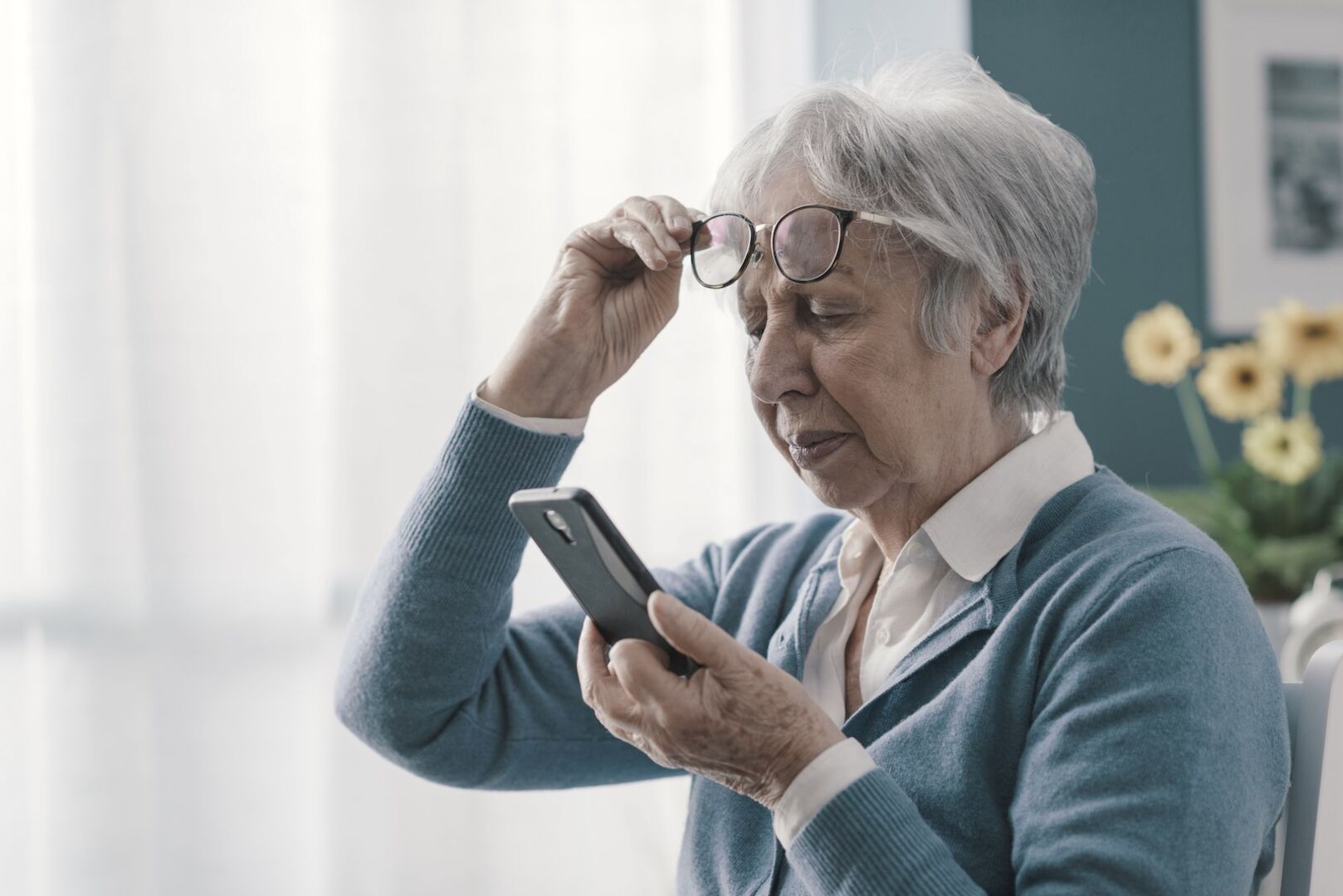 Eine Seniorin schaut misstrauisch auf ihr Handy.
