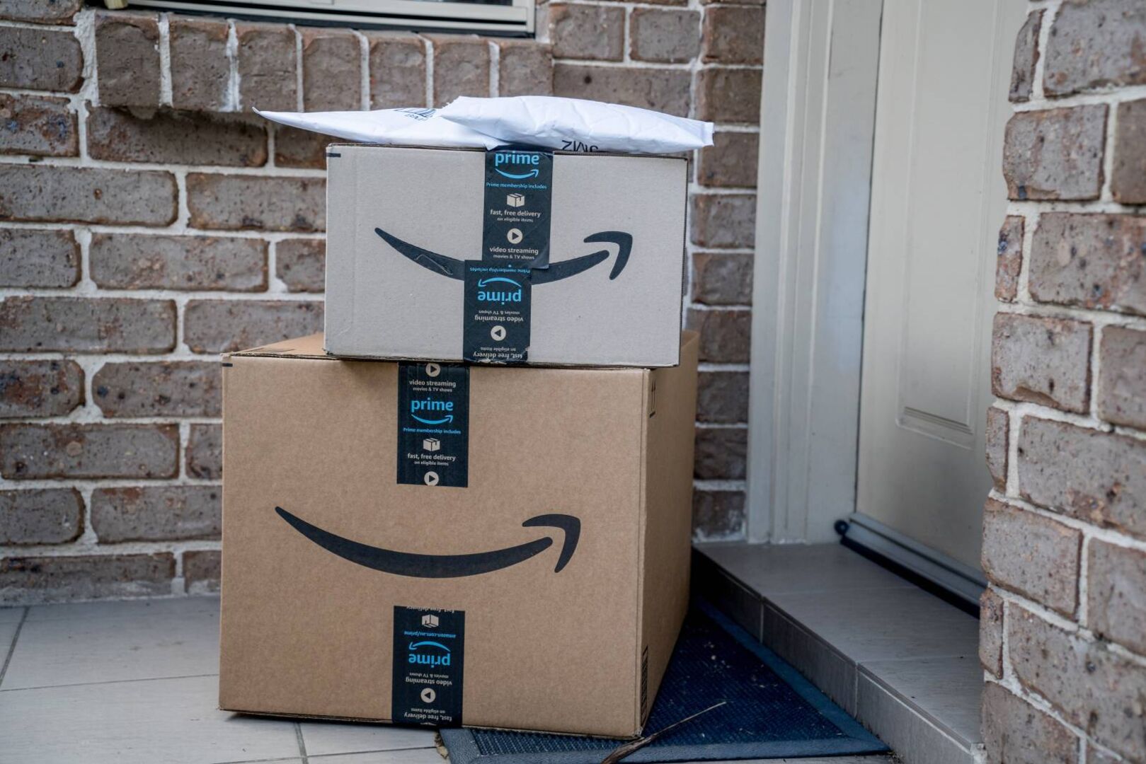 Zwei Amazon-Prime-Pakete übereinander gestapelt vor einer Haustür