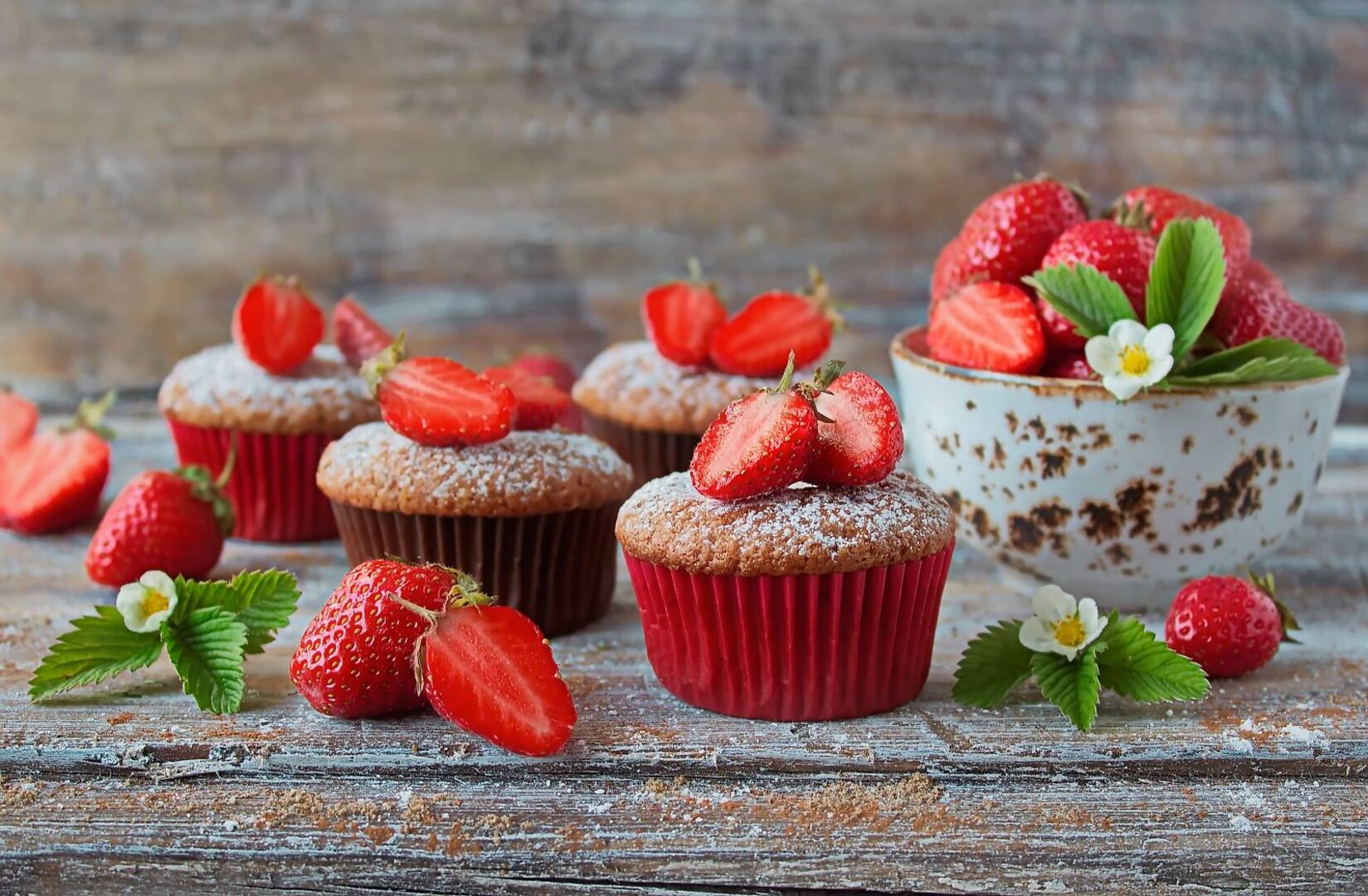 Erdbeer-Schoko-Muffins in einem roten Cupcake-Backförmchen, dekoriert mit frischen Erdbeeren.