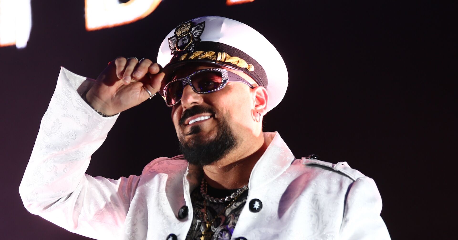 Gigi D'Agostino mit einer weißen Kappe und einer weißen Jacke on stage.