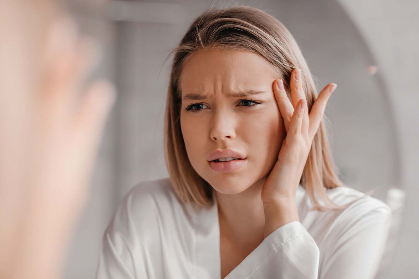 Frau schaut sich Falten im Spiegel an | Credit: iStock.com/Prostock-Studio