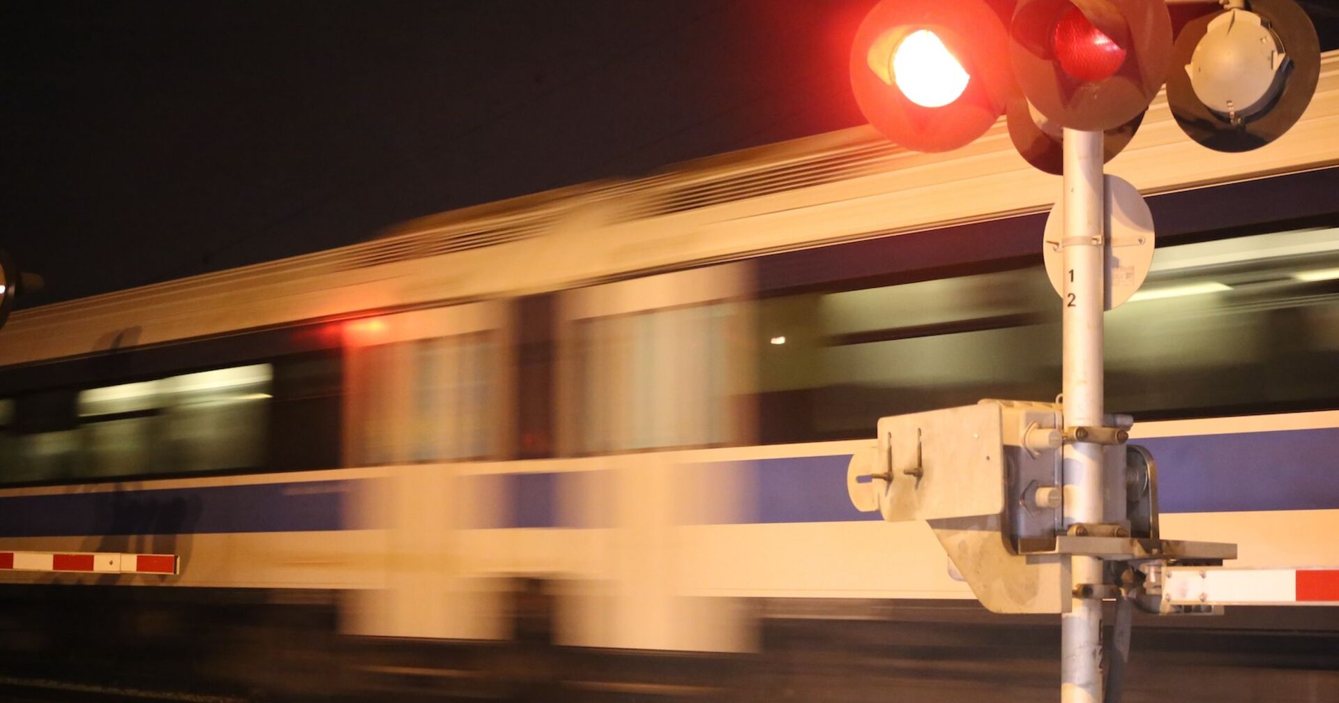 Mit Lichtzeichen geregelter Bahnübergang: Ein Zug braust vorbei.