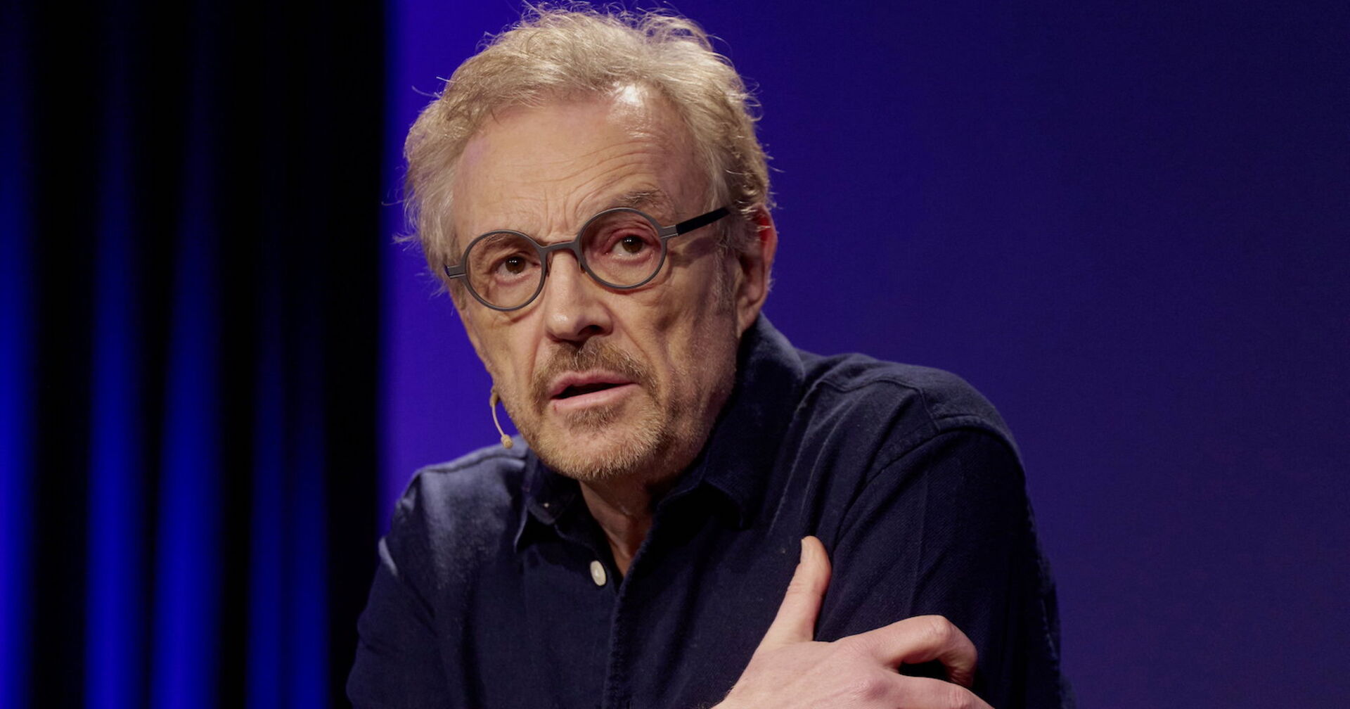 Josef Hader in einem schwarzen Hemd und einer Brille.