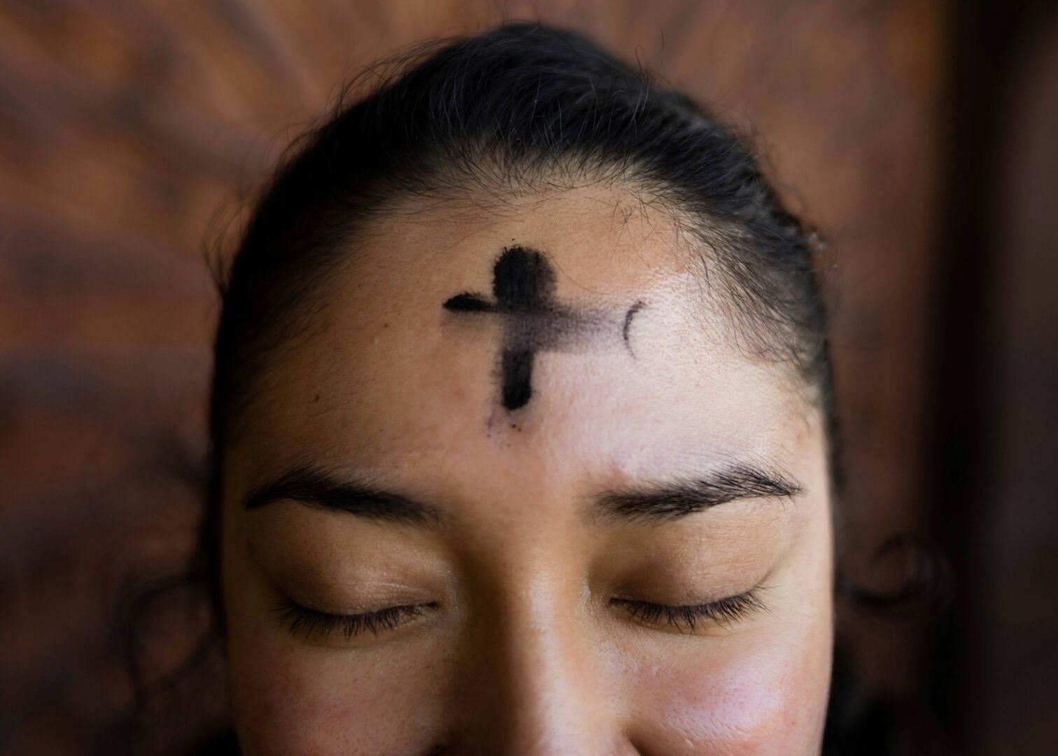 Ein Kreuz aus Asche auf einer Stirn.
