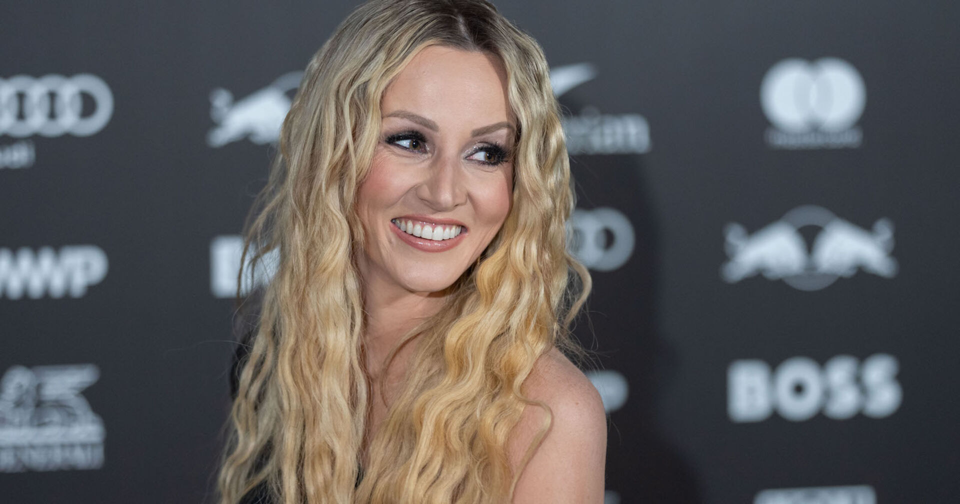 Melissa Naschenweng bei einem Event mit gewellten blonden langen Haaren und starken Augen Make-Up.