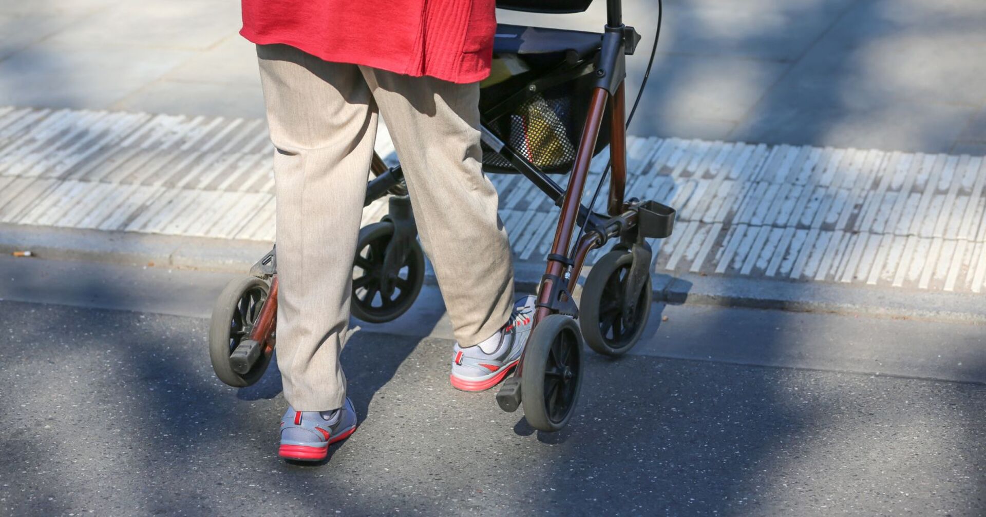 Eine Frau ist mit einem Rollator unterwegs.