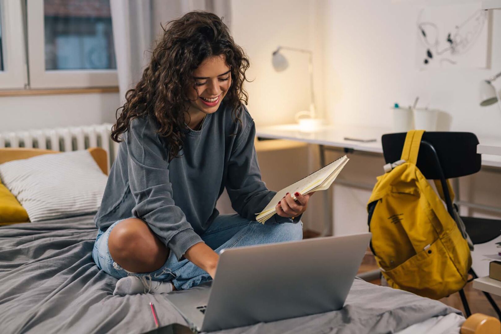 Studentin sitzt auf einem Bett | Credit: iStock.com/Dejan_Dundjerski