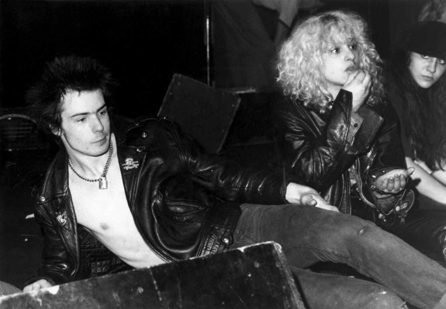 Schwarz-Weiß-Aufnahme von Sid Vicious und Nancy Spungen, die gemeinsam auf einer Konzertbühne sitzen