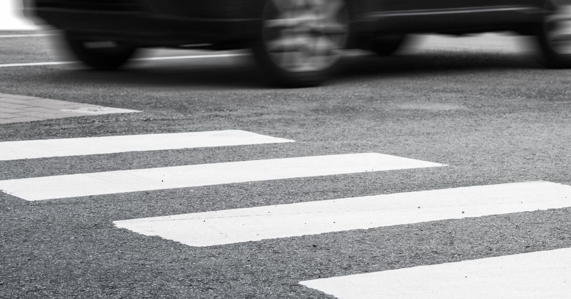 Eine Auto braust auf einem Zebrastreifen davon.