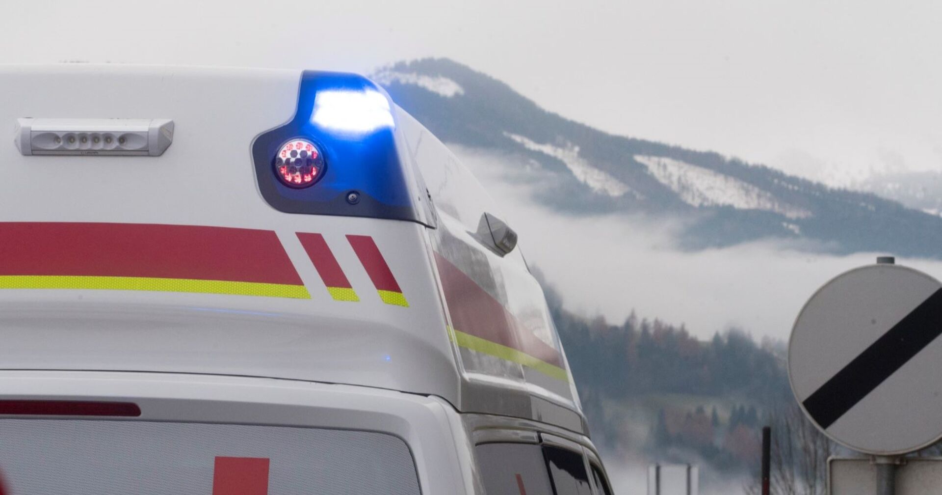 Blaulicht eines Rettungswagens vor verschneiten Bergen