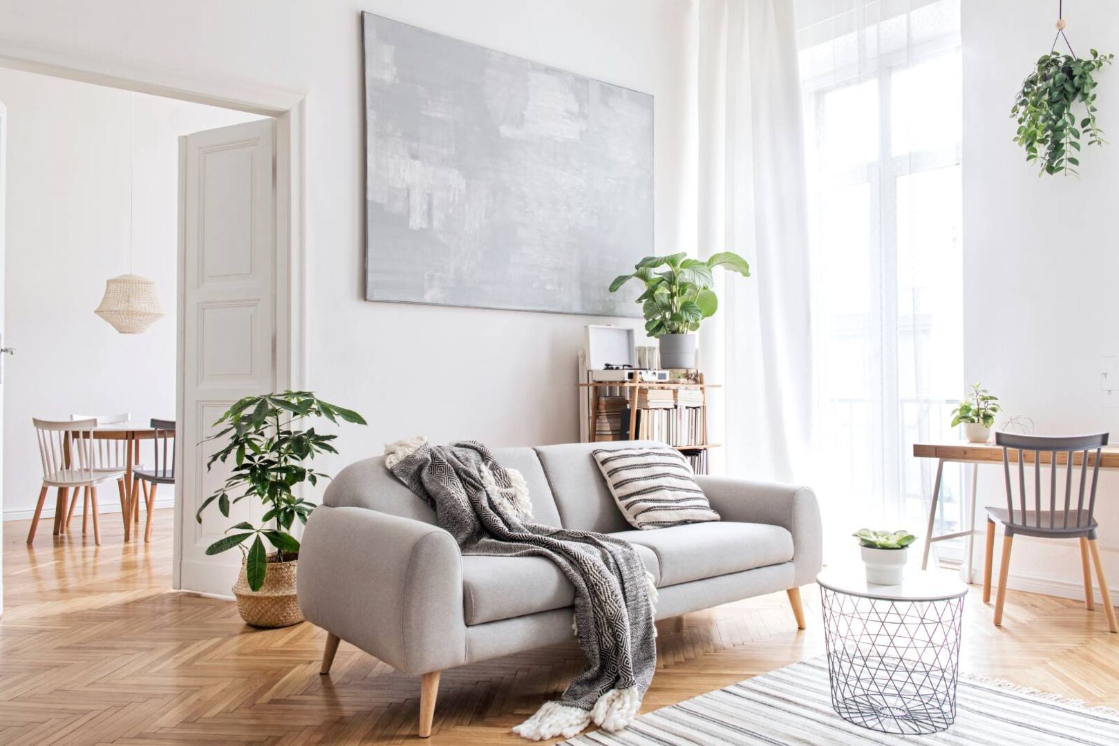 Wohnzimmer, welches mit einem grauen Sofa und Pflanzen im Hintergrund ausgestattet ist
