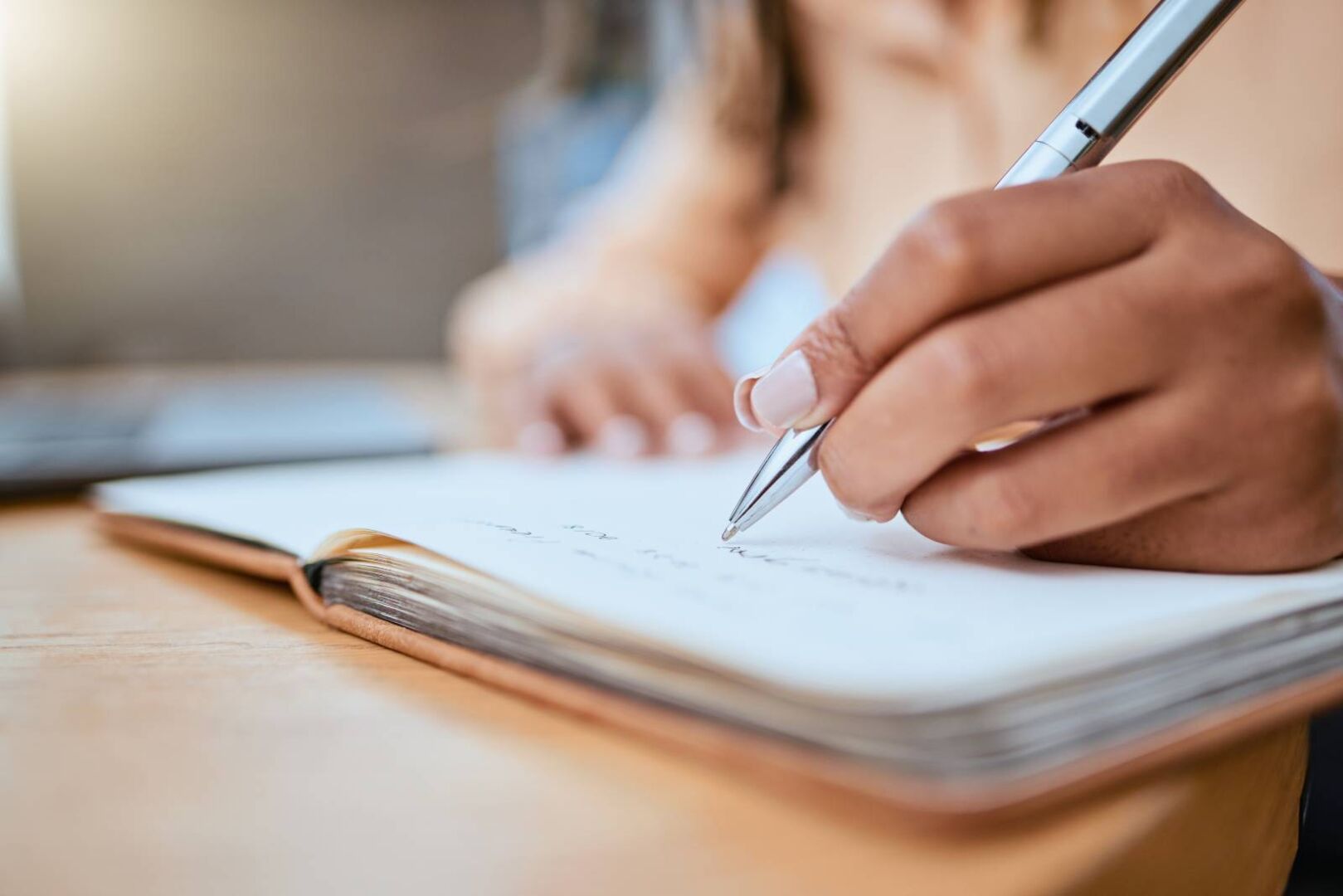Nahaufnahme der Hand einer Person, die etwas in ein Notizbuch schreibt