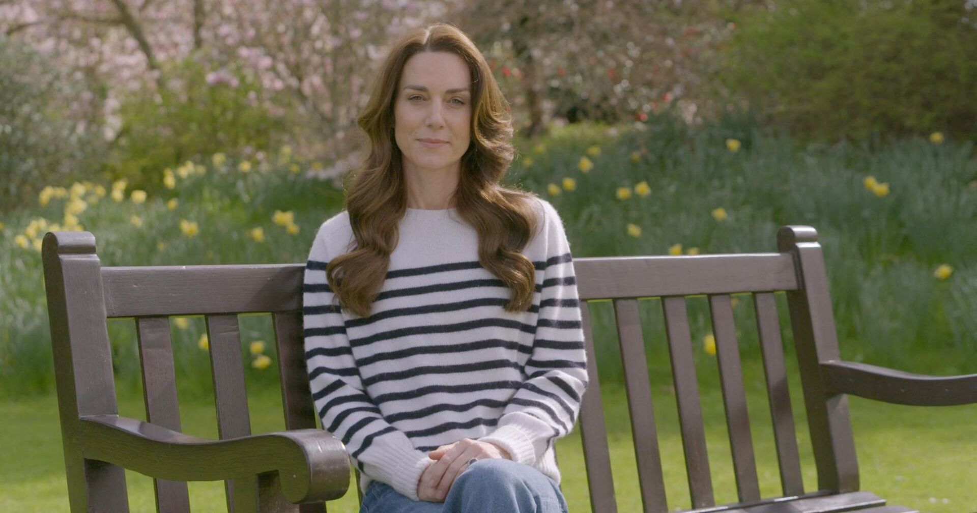 Prinzessin Kate sitzt auf einer Bank im Garten.
