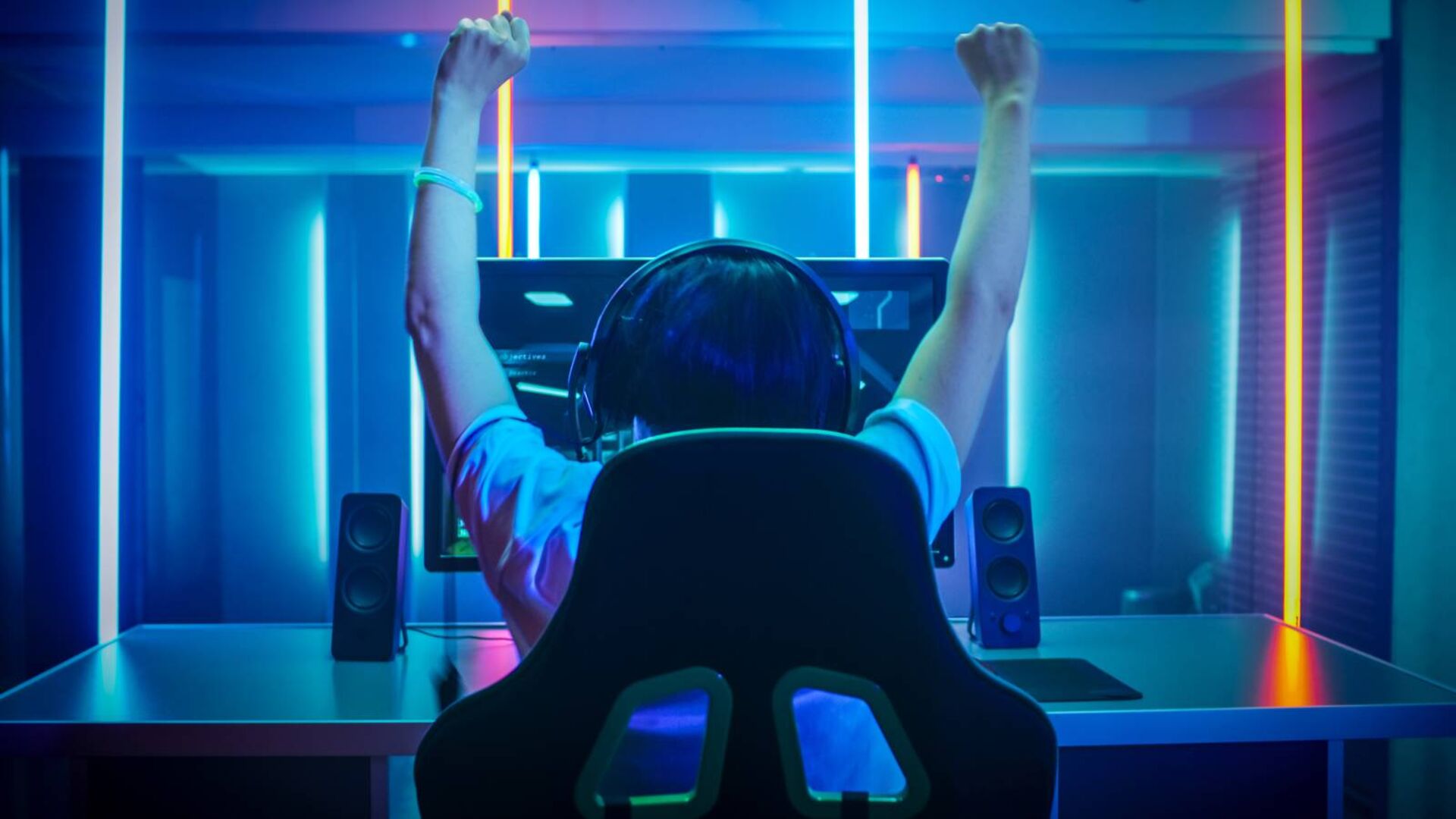 Rückenansicht eines Gamers, der gerade ein Spiel gewonnen hat und vor Freude die Hände in die Höhe reckt.
