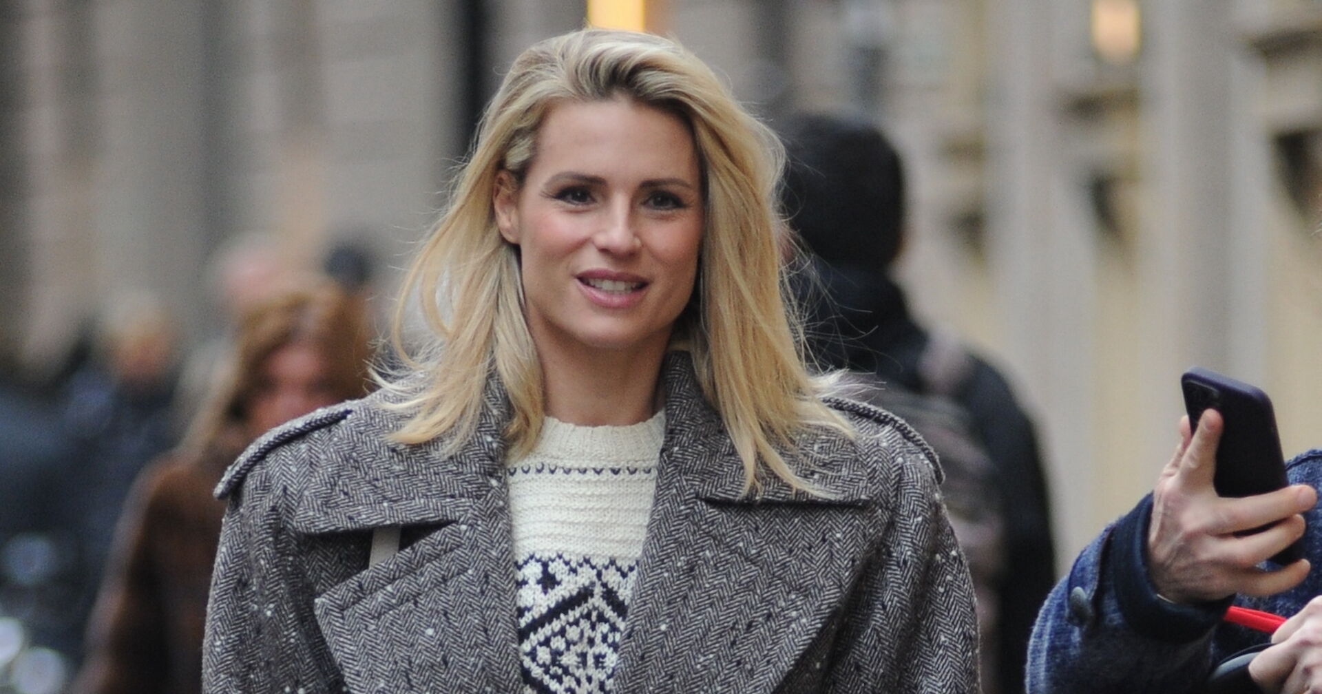 Michelle Hunziker mit offenen blonden Haaren und einem grauen Mantel.