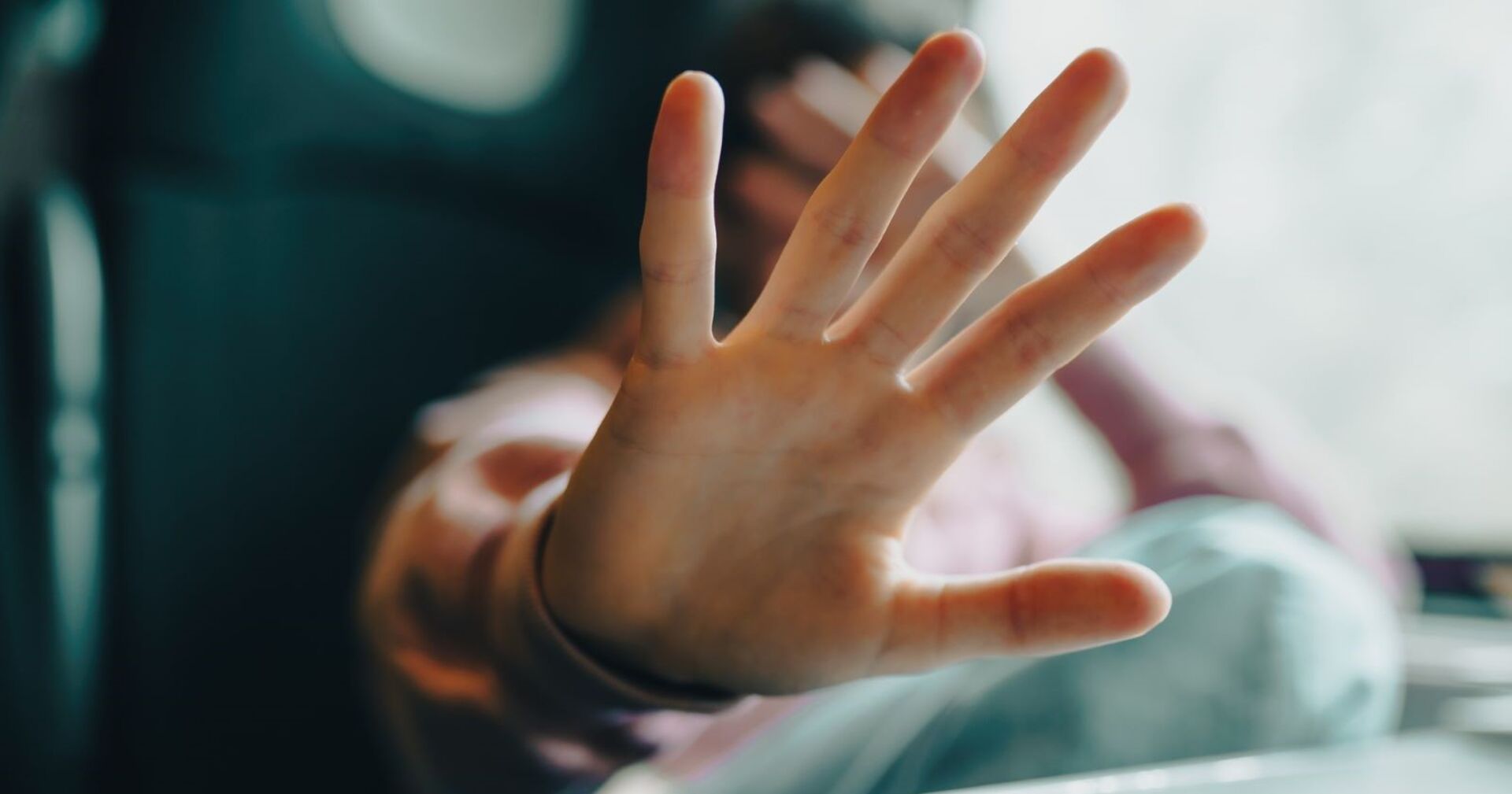 Ein Mädchen signalisiet mit einer ausgestreckten Hand "Stopp". Die andere hat sie verzweifelt über ihr Gesicht gelg.