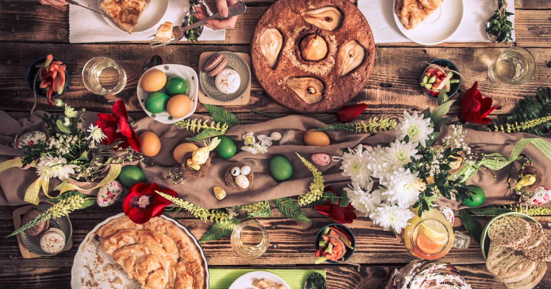 Bunt gedeckter Ostertisch mit traditionellen Speisen, gekochten Eiern und Tischdekoration in Erdtönen