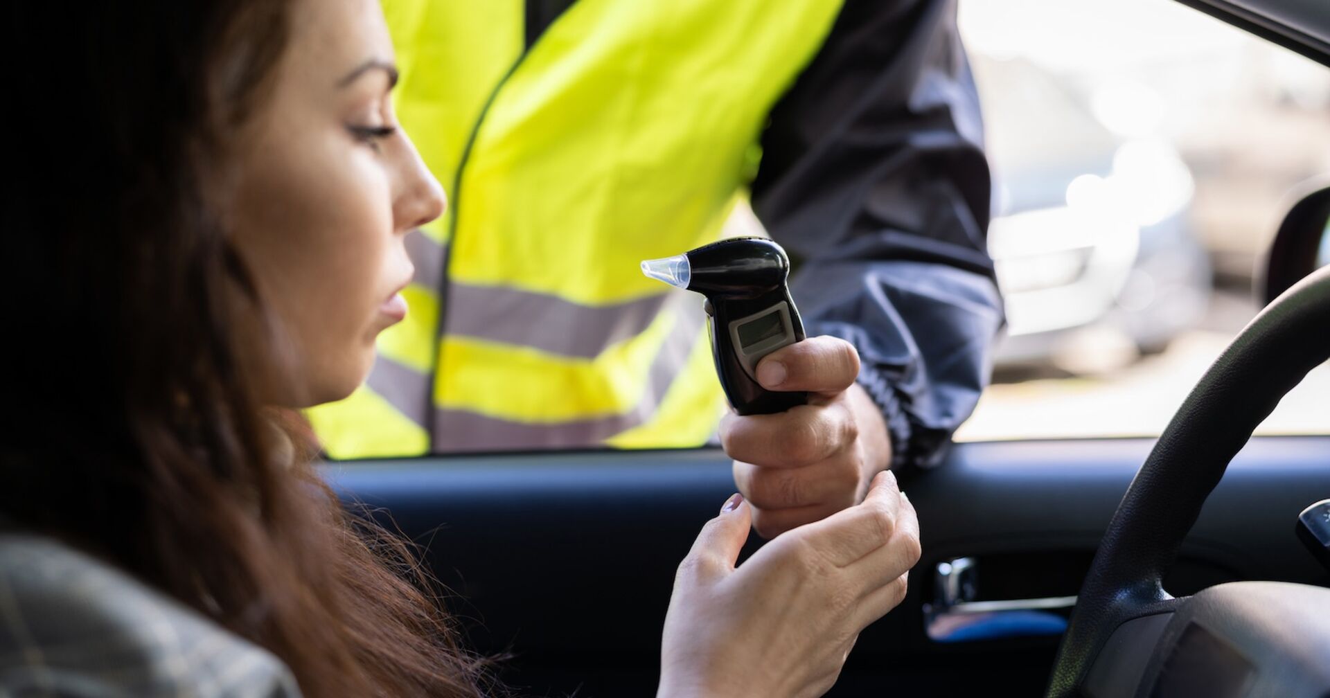 Ein Polizist führt bei einer Frau einen Alkotest durch.