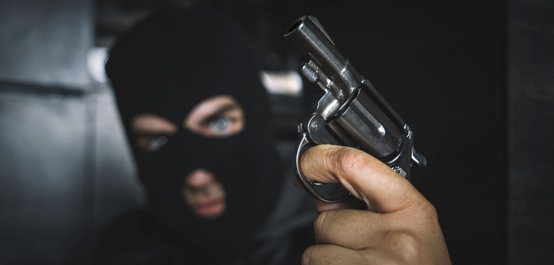 Ein Einbrecher mit einer Pistole in der Hand.