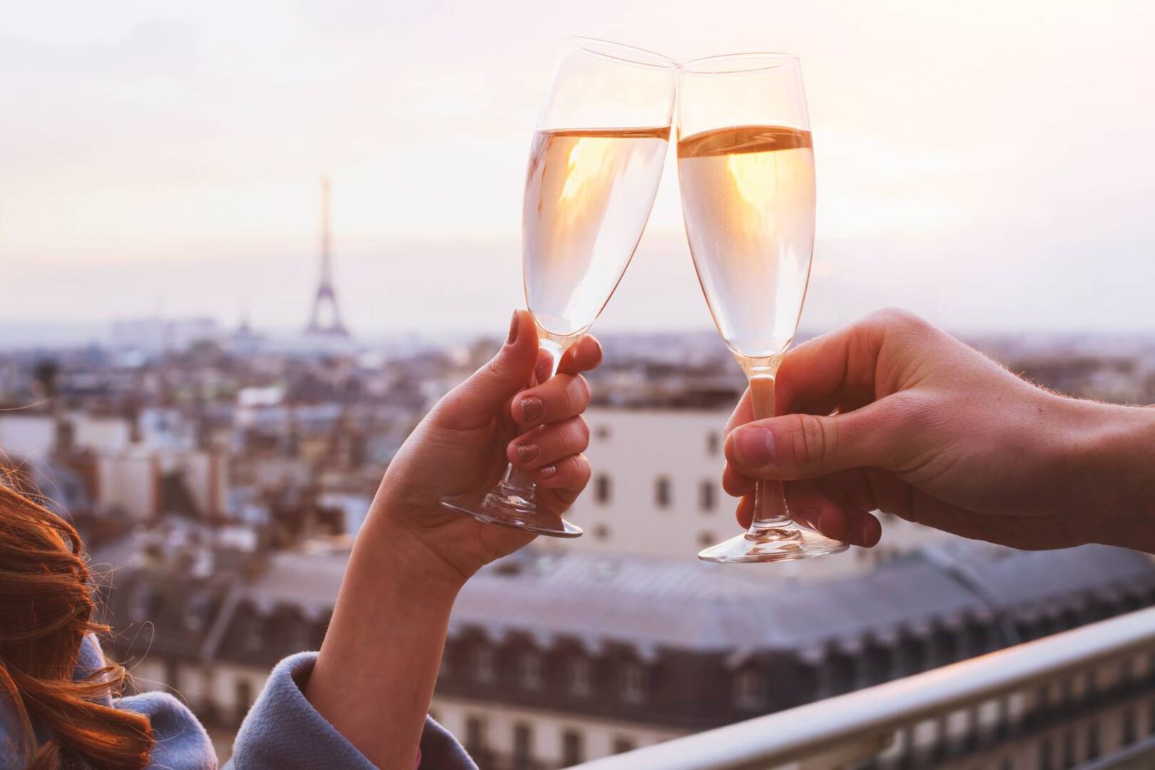 Nahaufnahme eines Champagner trinkenden Paares, in der Ferne ist der Eiffelturm in Paris zu sehen.