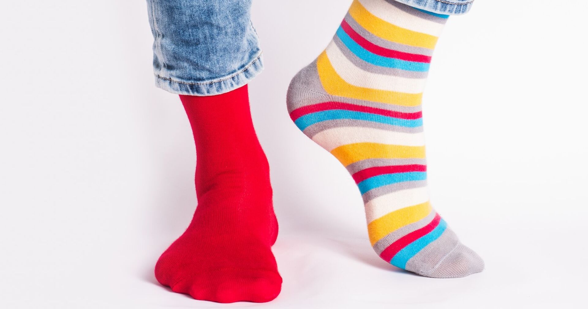 Jemand, der einen roten und einen bunt gestreiften Socken trägt.