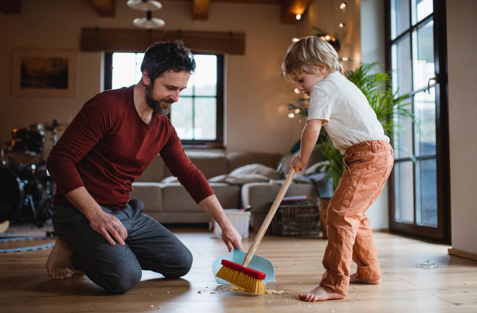 Vater und Sohn reinigen gemeinsam den Fußboden im Wohnzimmer