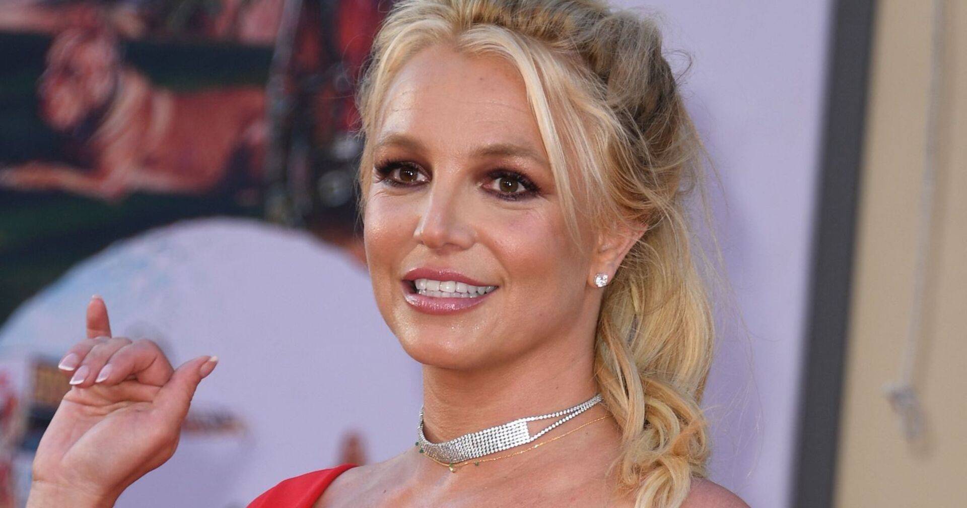Britney Spears mit geschlossenen blonden Haaren und einer glitzer Kette.