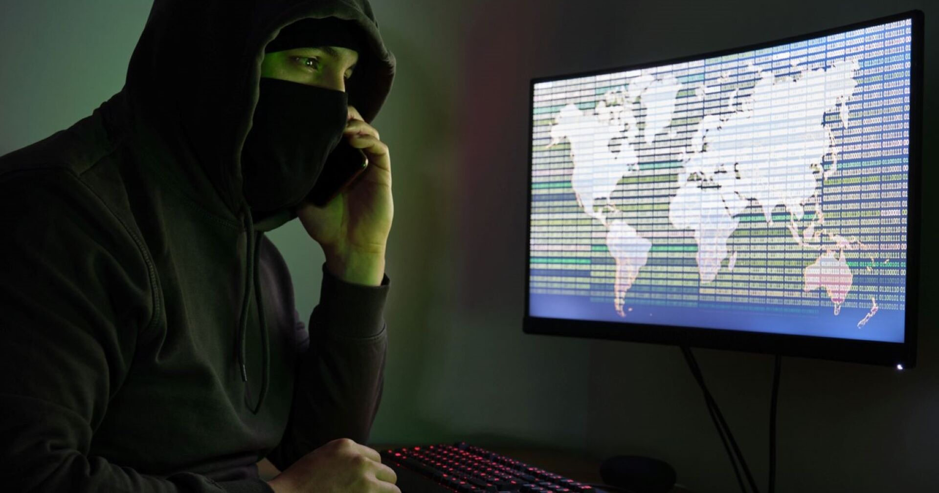 Ein vermummter junger Bursche mit einem Handy in der Hand.