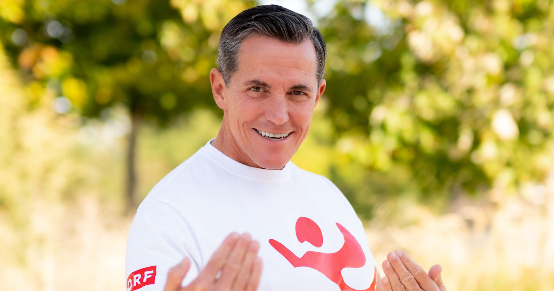 Philipp Jelinek in der Natur, er trägt ein weißes ORF-T-Shirt und posiert in Bewegung für die Kamera