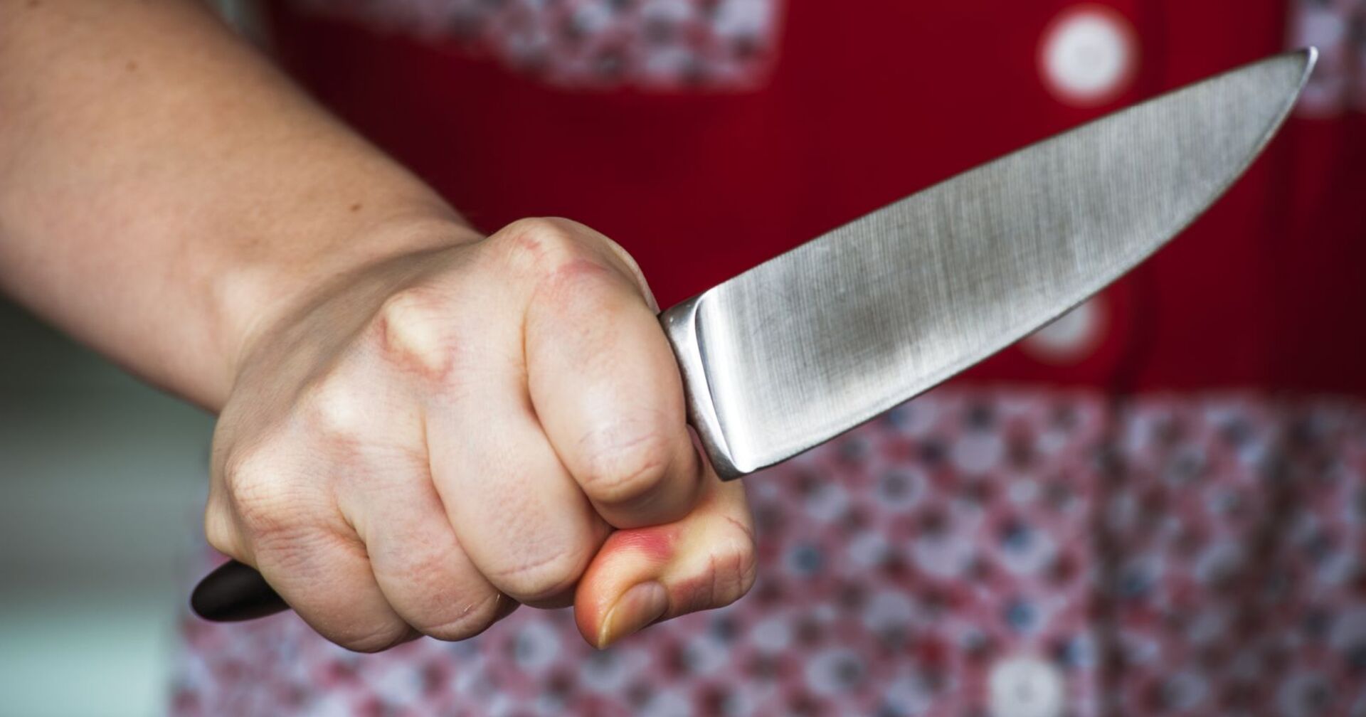 Eine Frau hält ein Küchenmesser bedrohlich in der Hand.