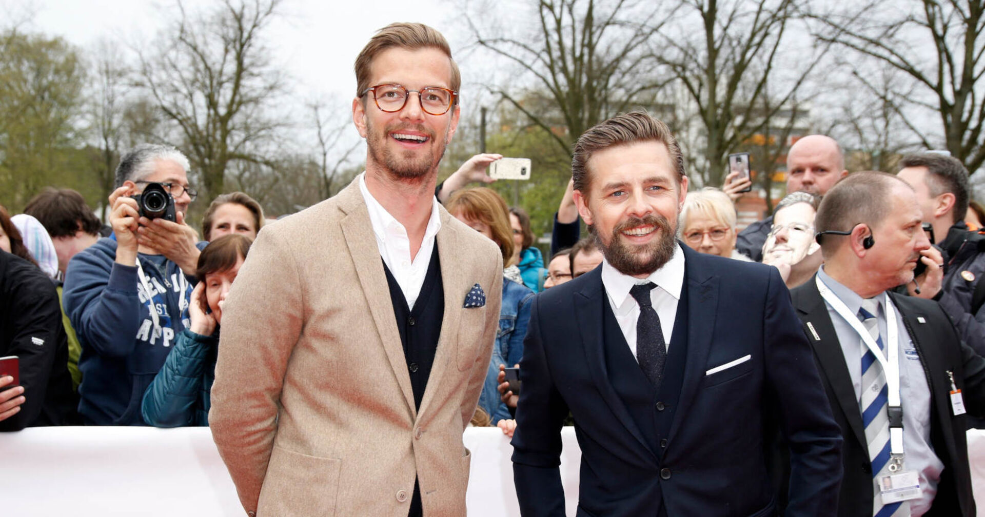 Zwei Männer in Anzügen lachen in die Kamera