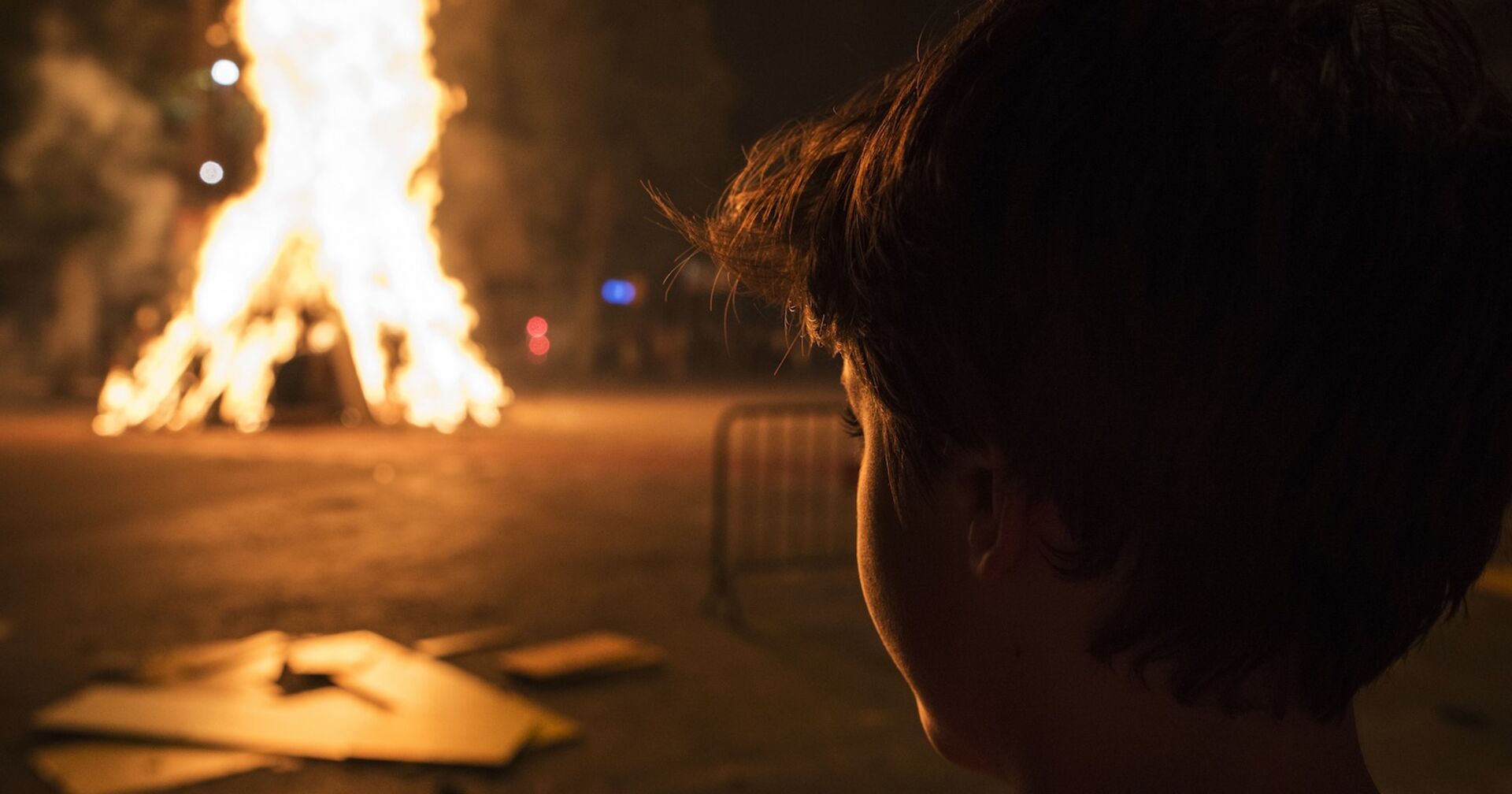 Ein kleiner Bub beobachtet ein großes Feuer.