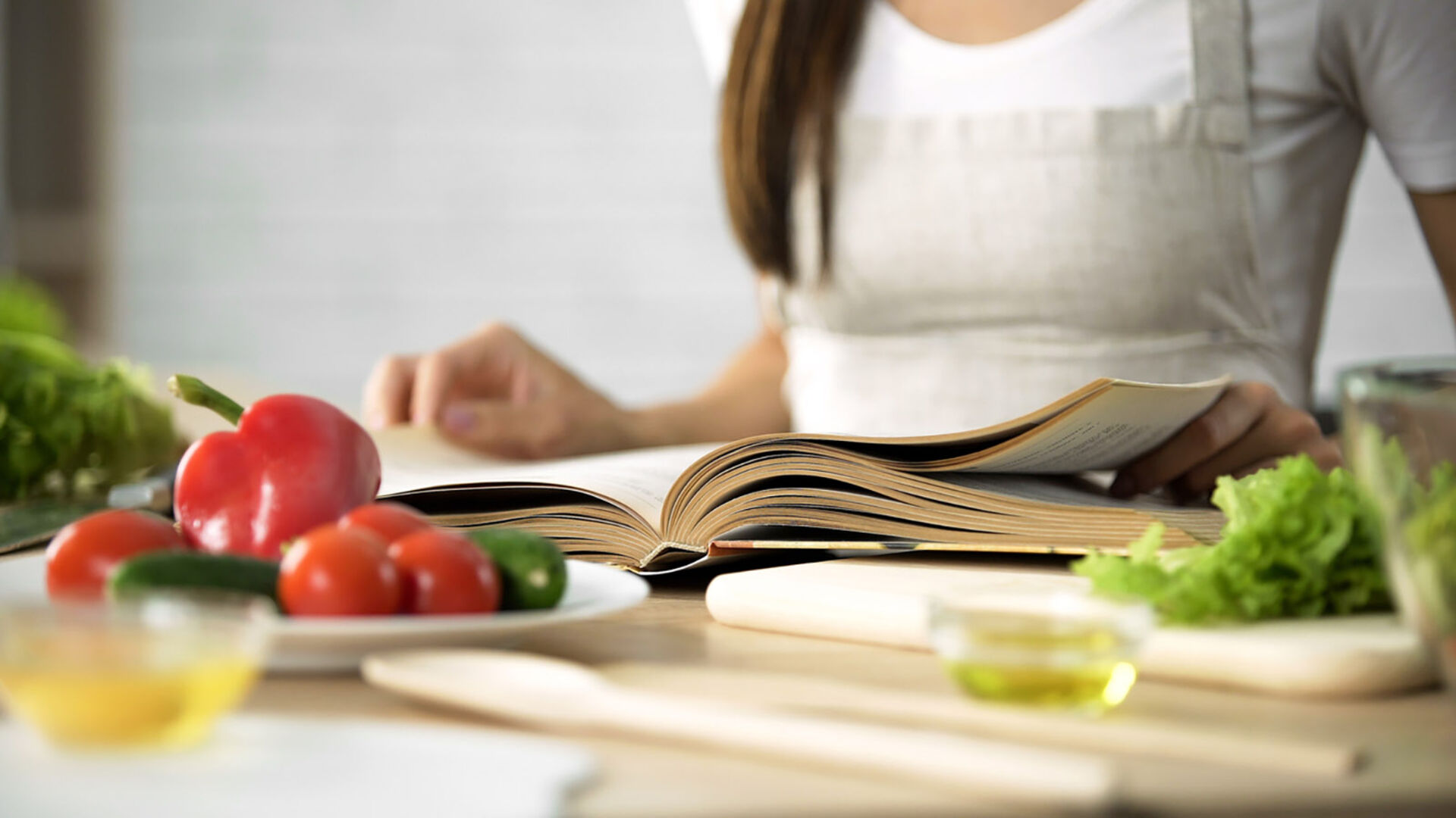 Frau blättert im Kochbuch | Credit: iStock.com/Motortion