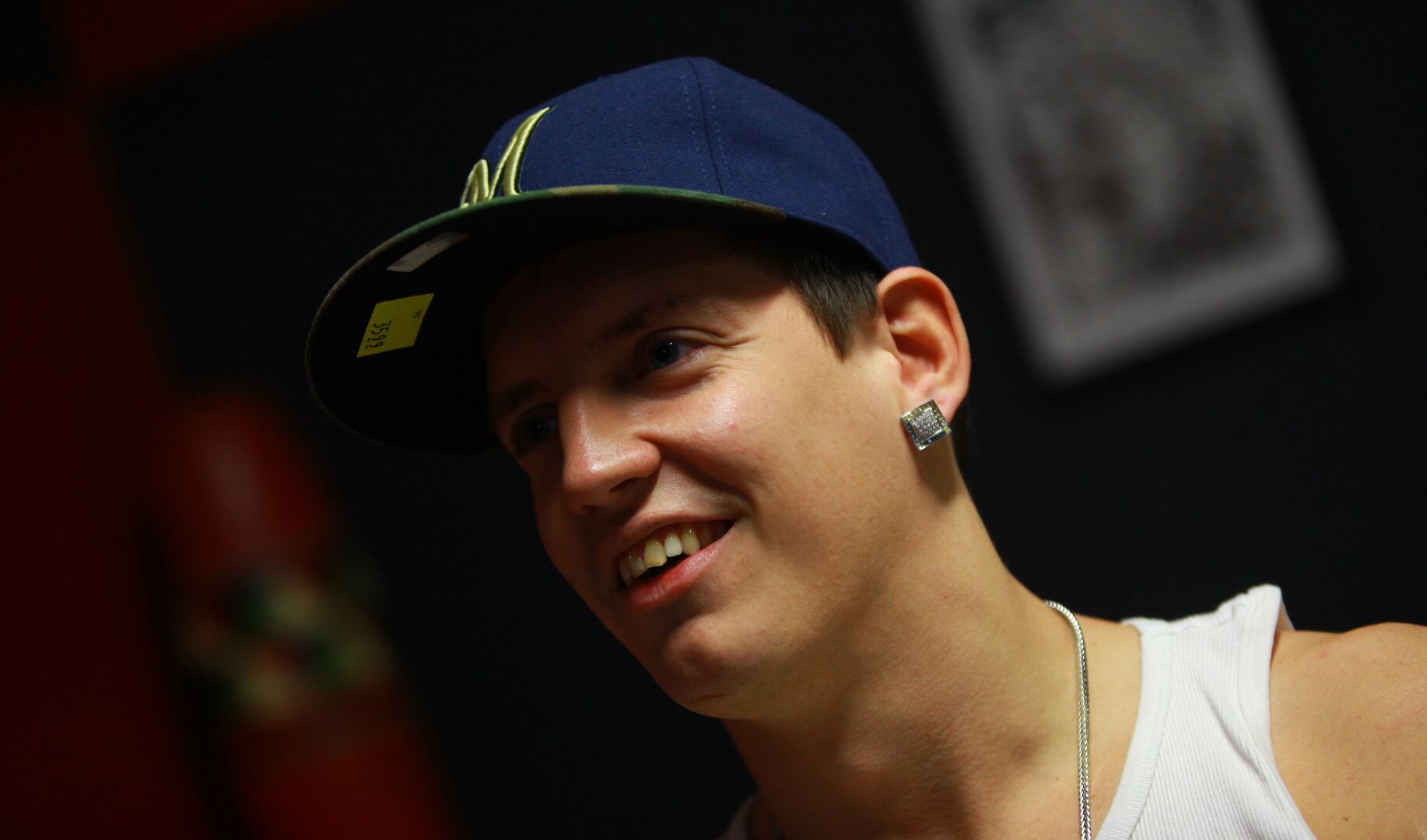 Money Boy mit einer Kappe und einem weißen Trägershirt.