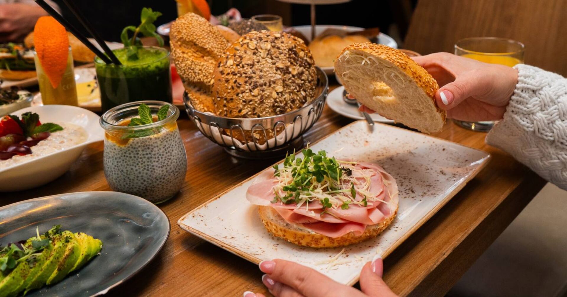 Reich gedeckter Frühstückstisch mit einem Bagel mit Schinken, frischem Meerrettich und Kräutern.