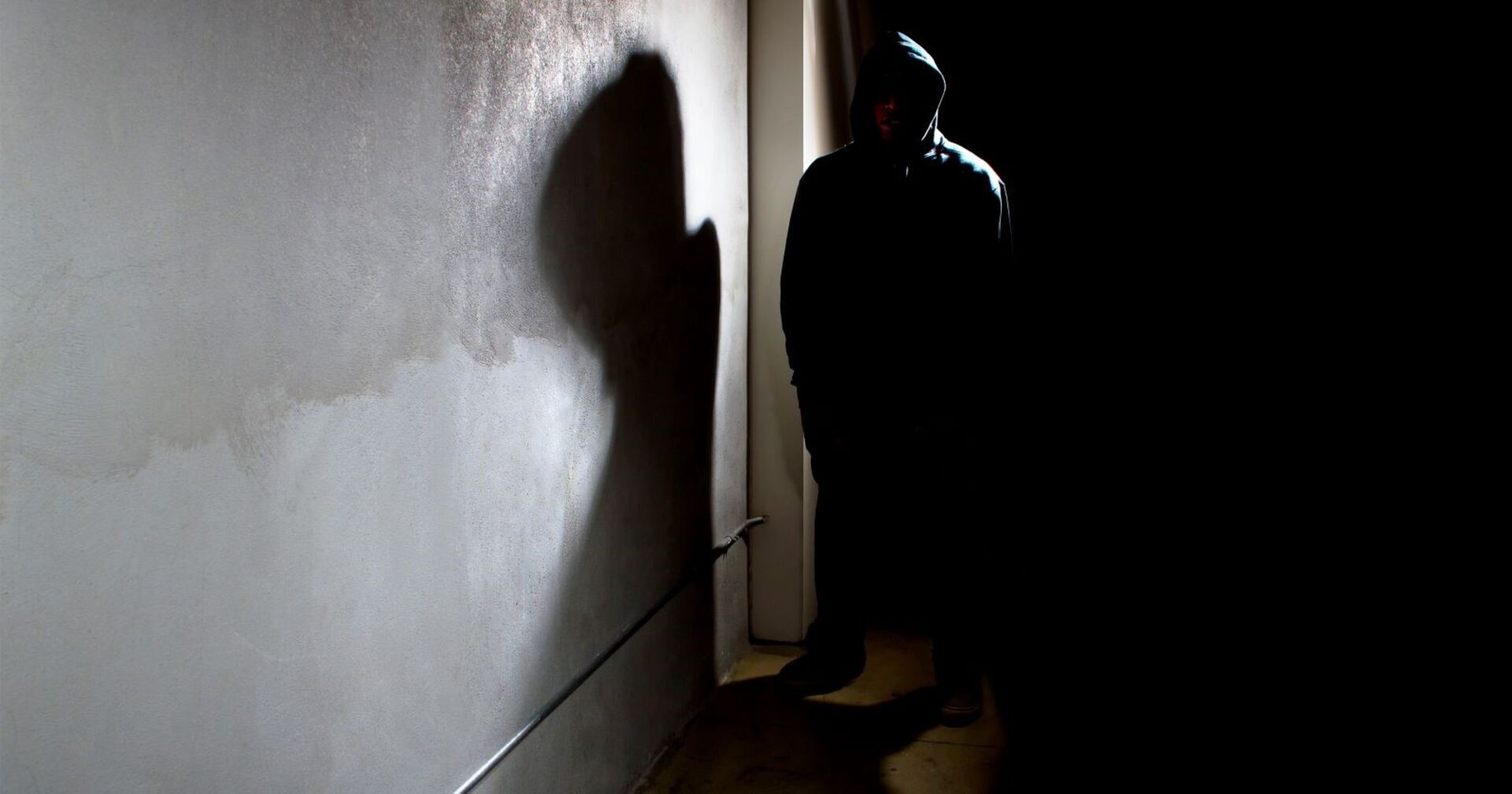 Ein Räuber mit Kapuze in einer dunkeln Gasse.